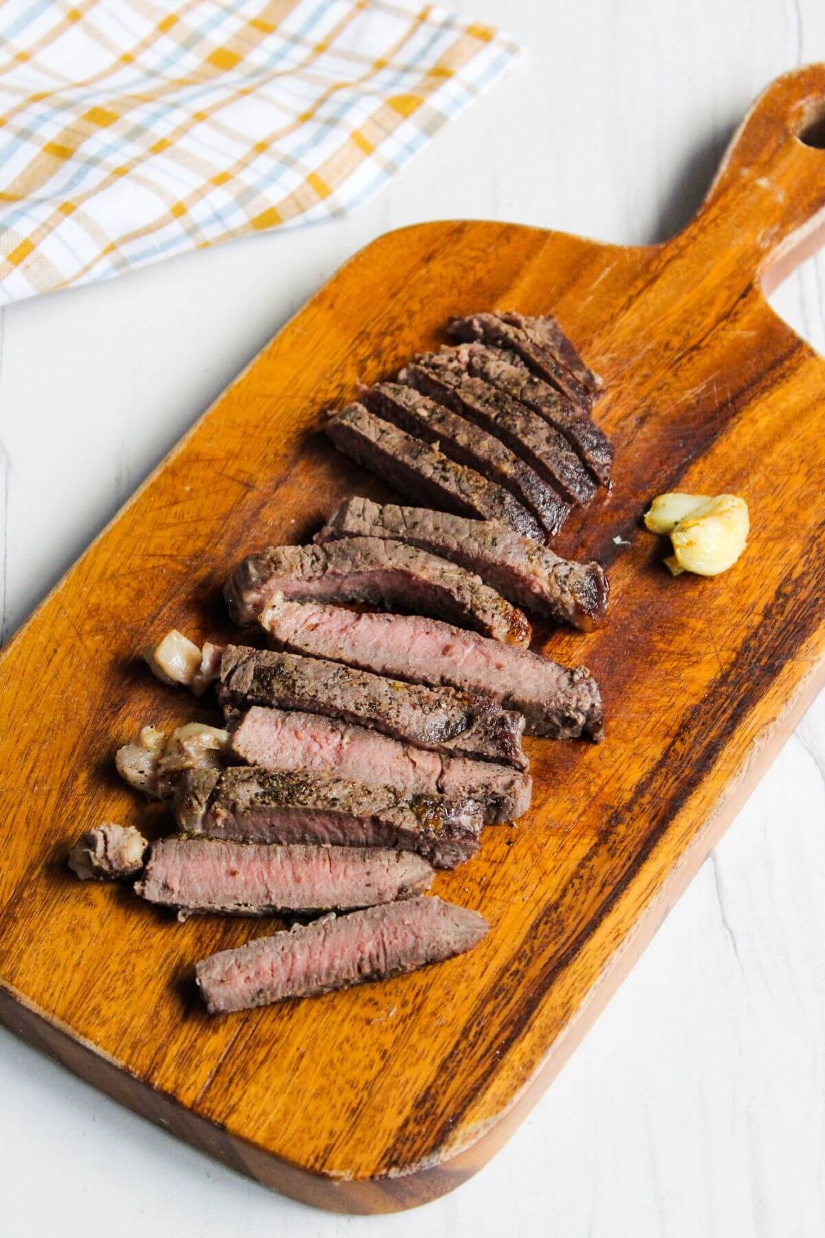 Sliced steak on wood cutting board.