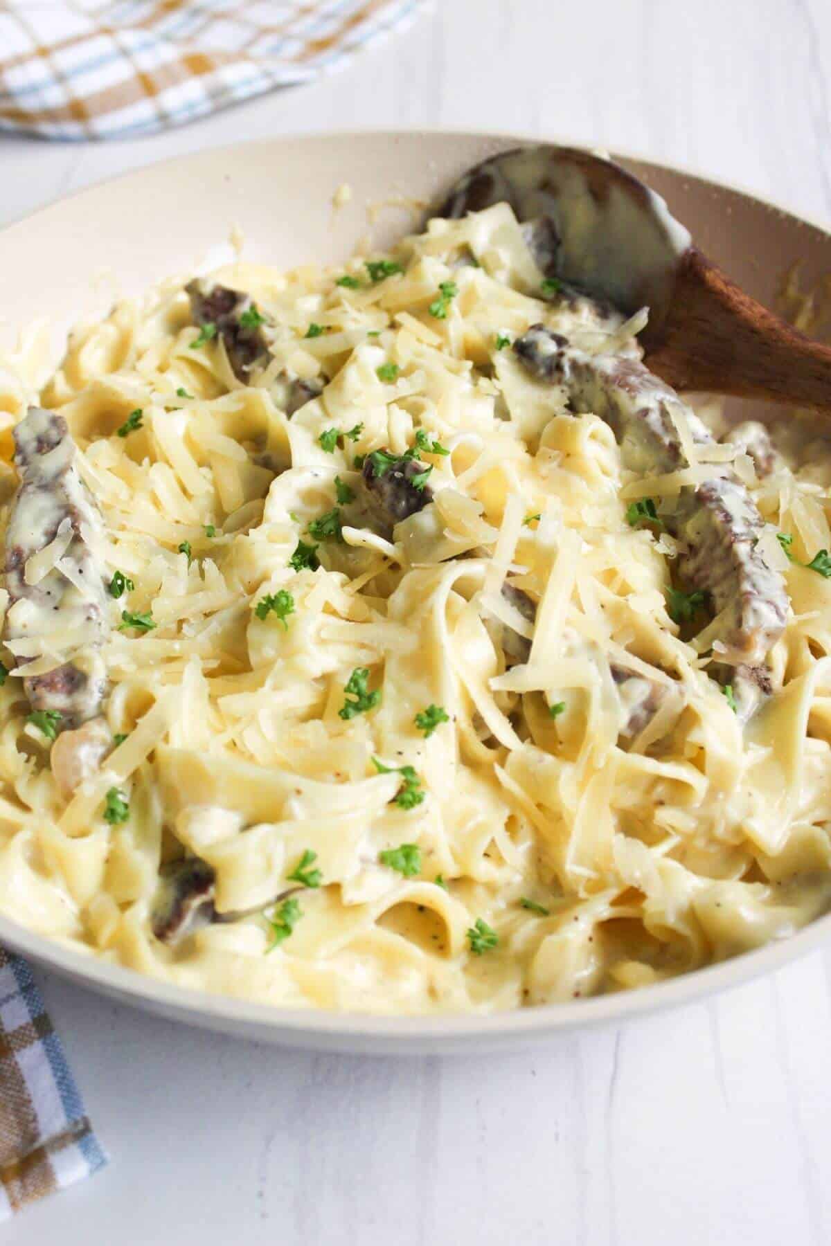 Skillet with pasta and steak in Alfredo sauce.