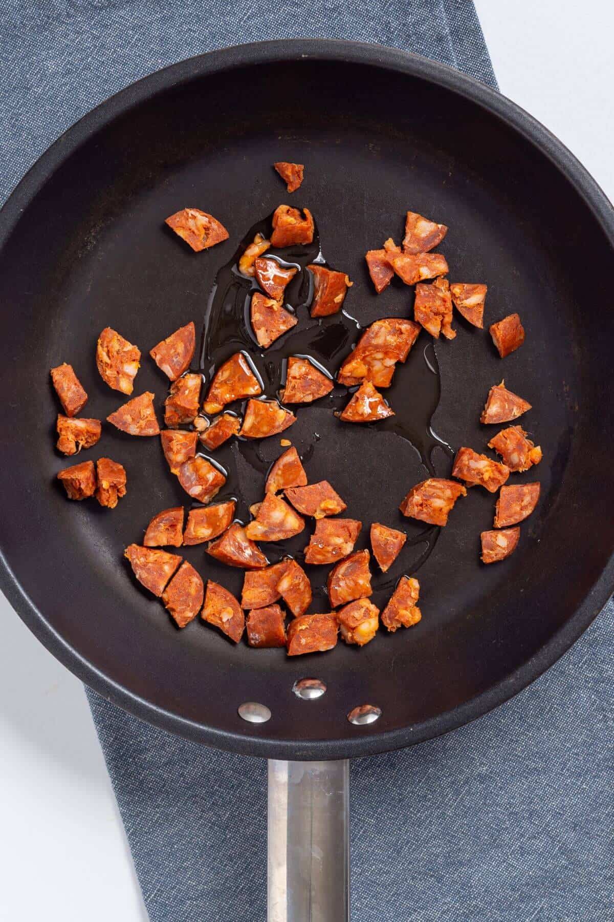 Chorizo pieces cooking in skillet.