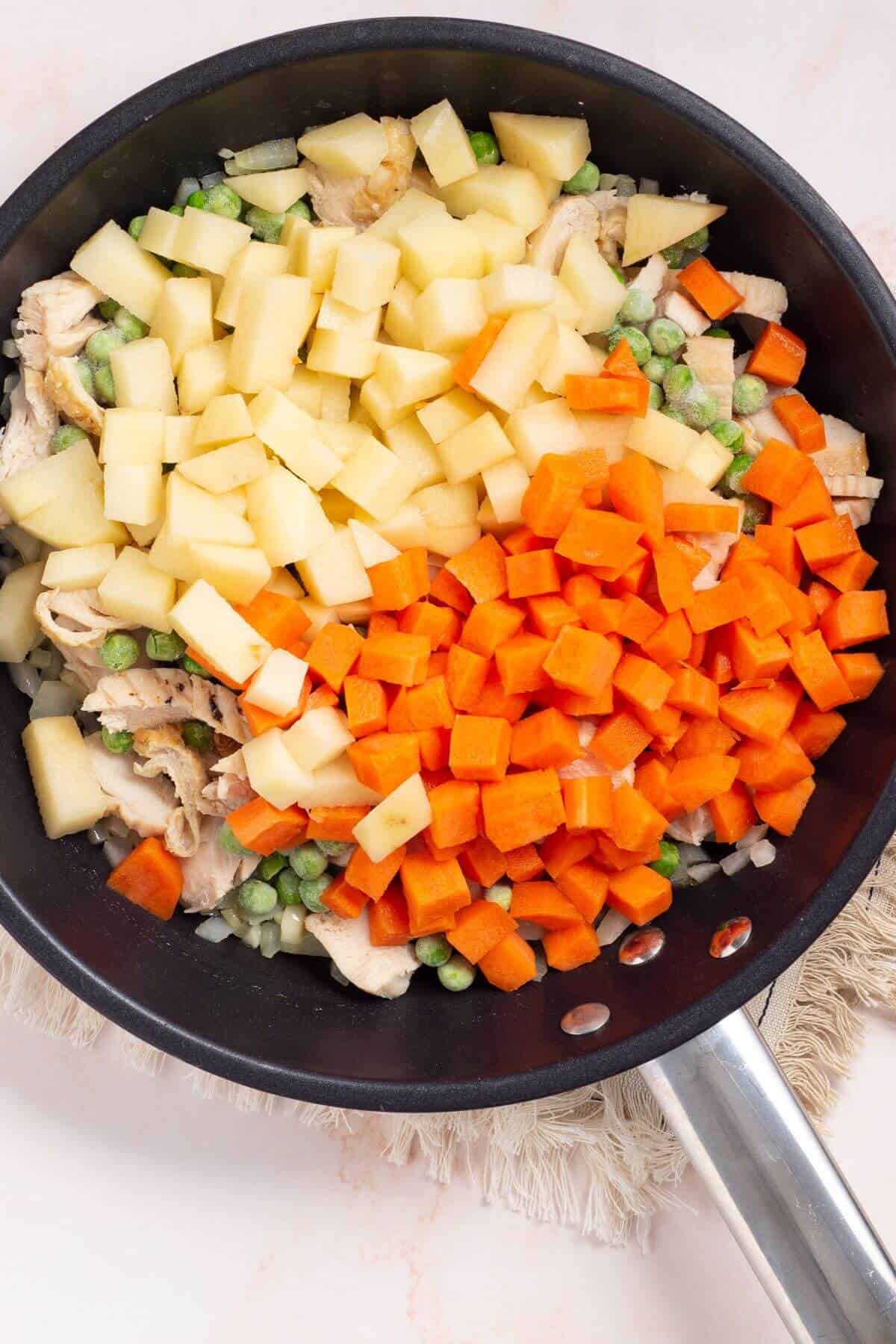 Chicken, peas, carrots, and potatoes added to skillet.