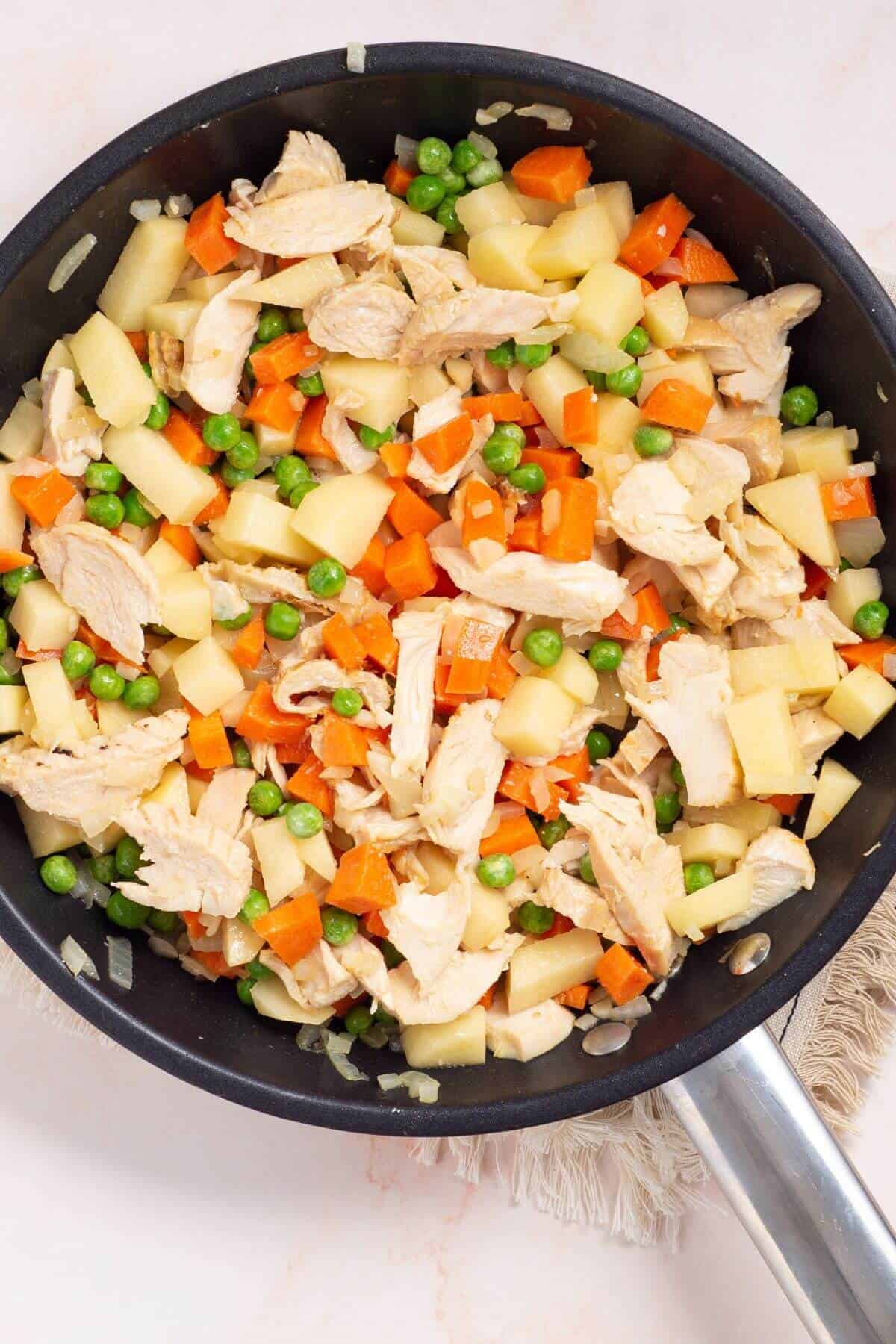 Vegetables and chicken combined in skillet.