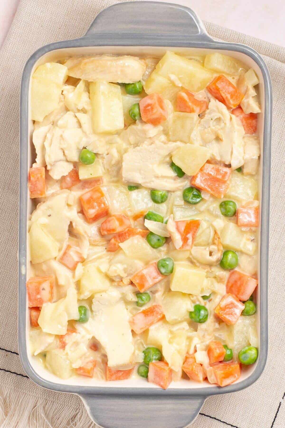 Chicken pot pie filling added to small casserole pan.
