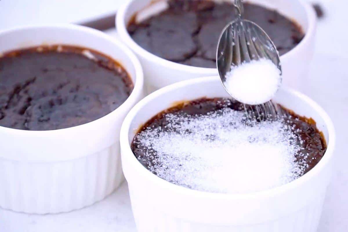 Sprinkling sugar over the top of the chocolate creme brulee.