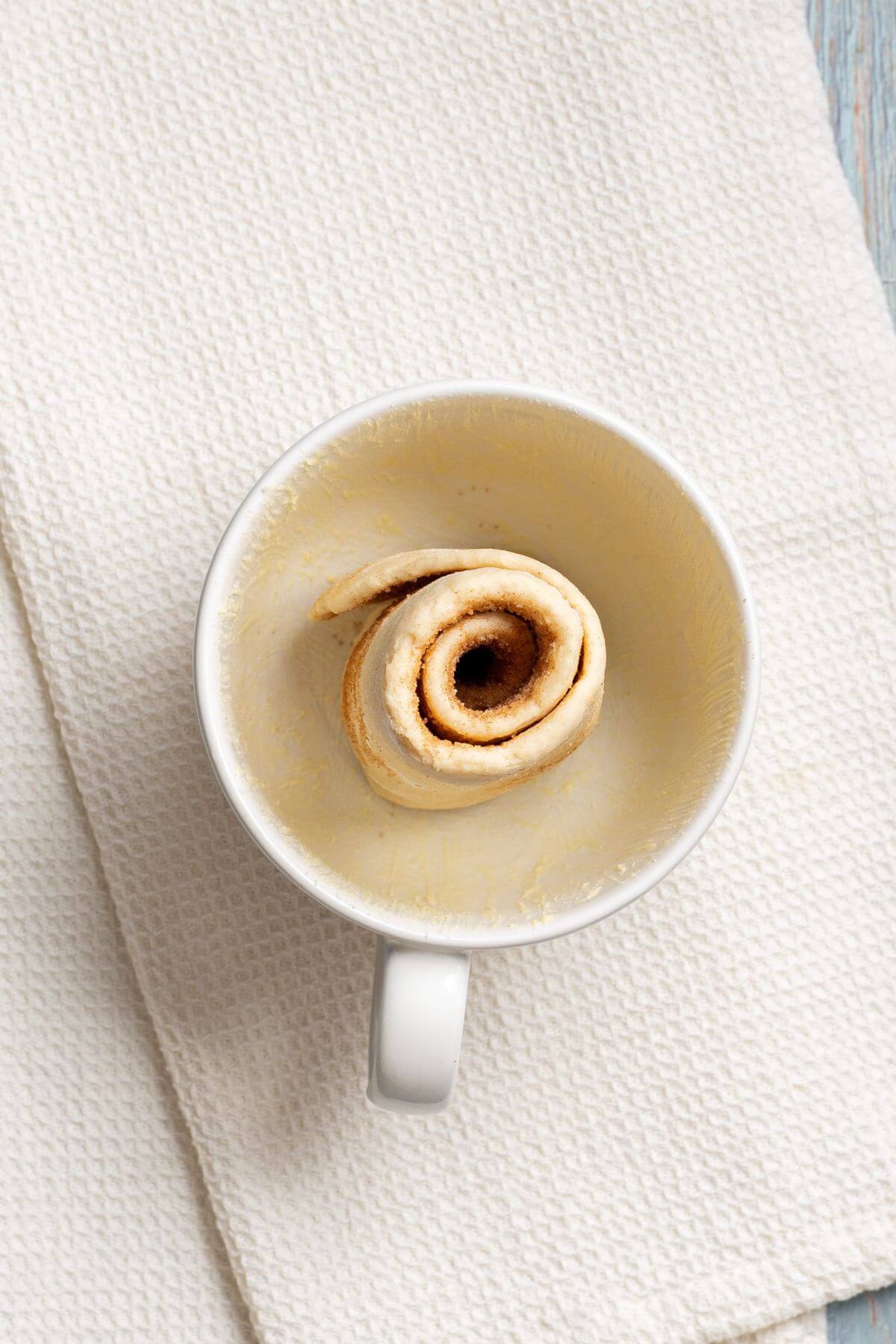 Unbaked cinnamon roll in coffee cup.