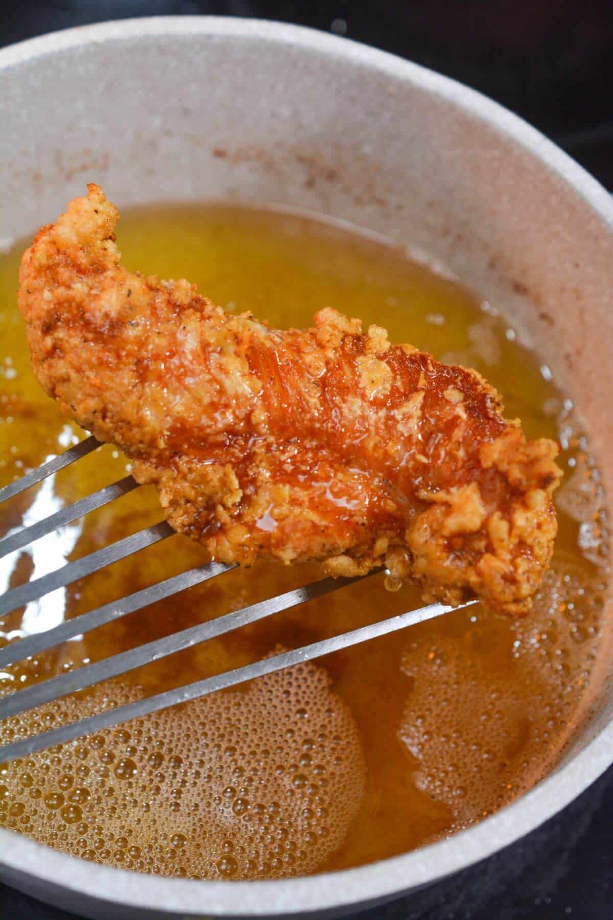 Removing fried chicken from oil.