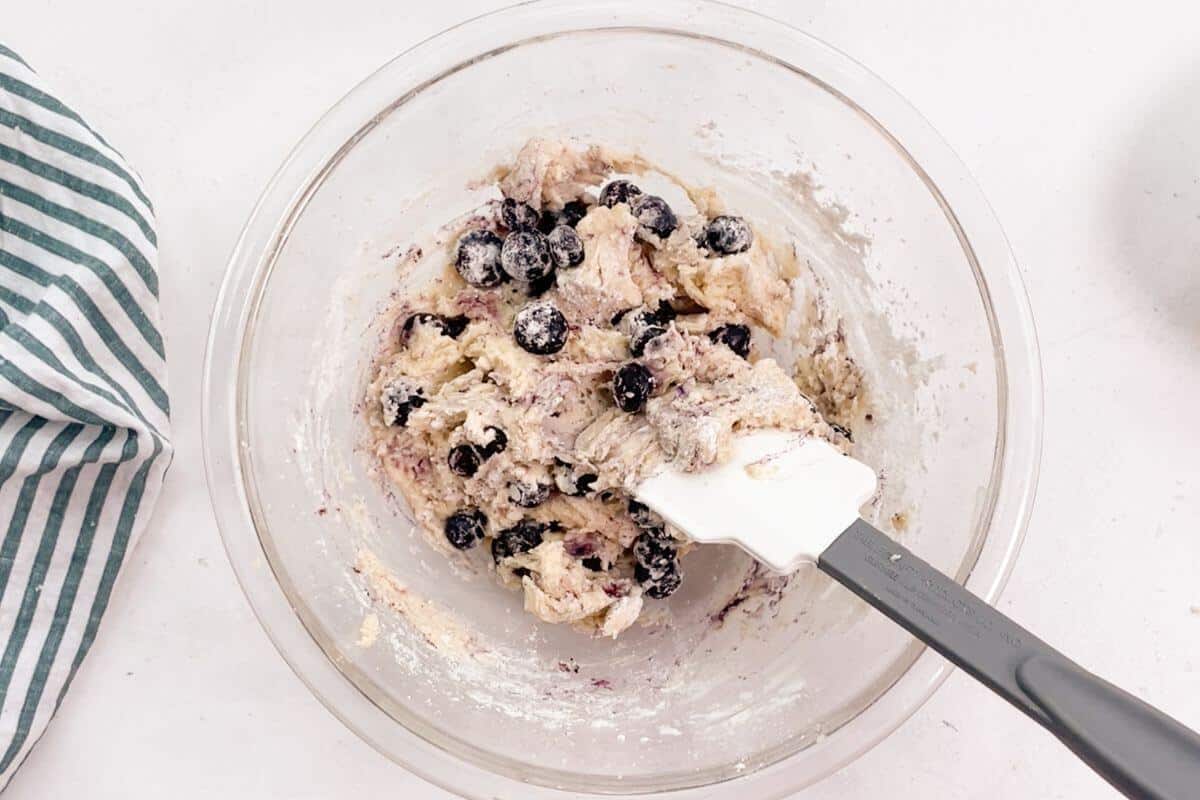 Folding blueberries into batter gently.