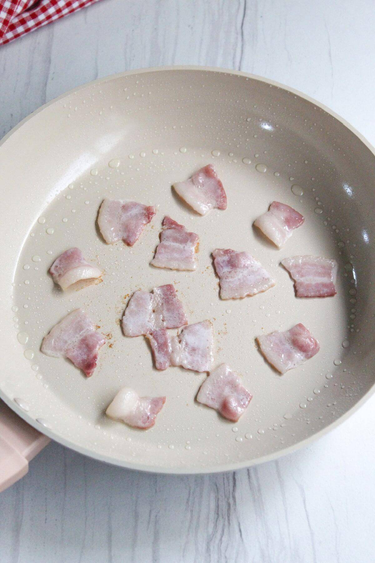 Cooking bacon pieces in skillet.
