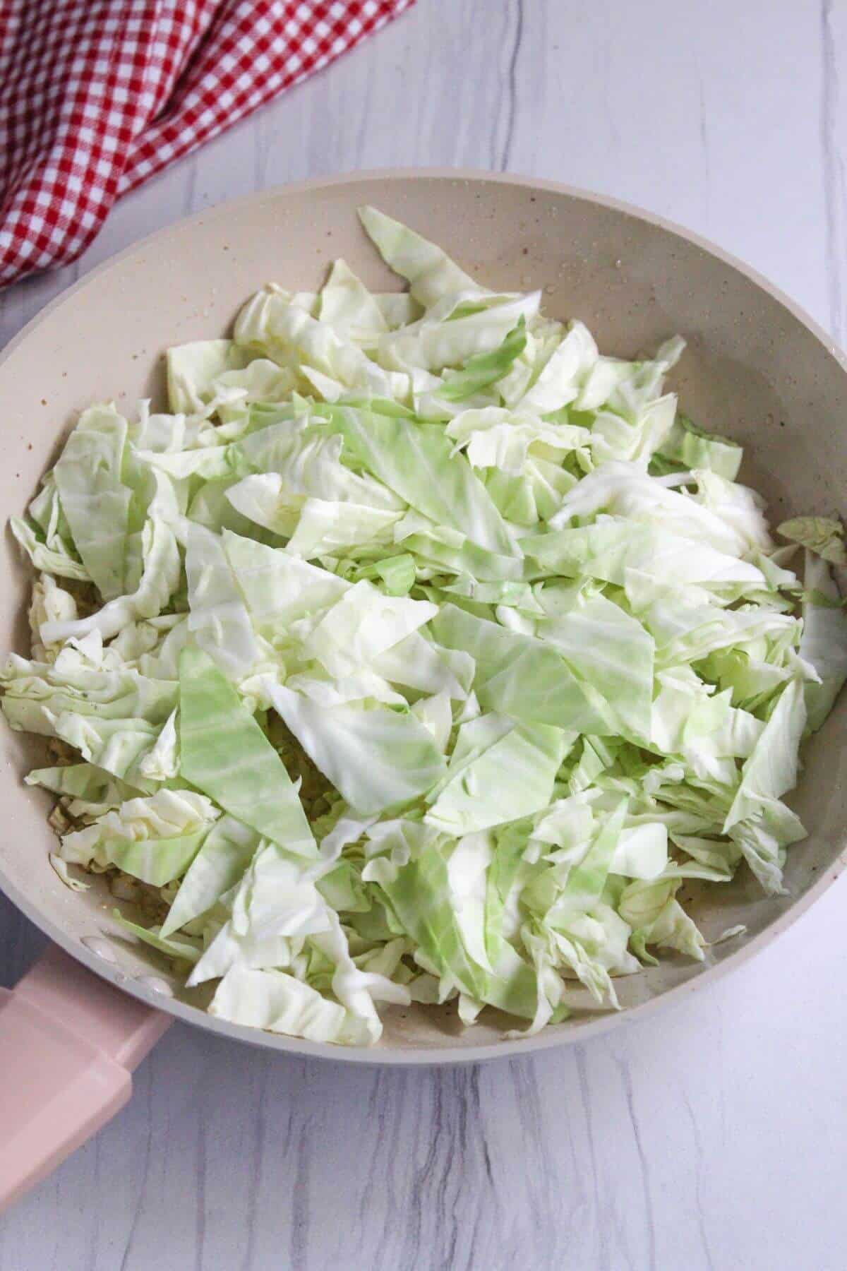 Chopped cabbage added to skillet.