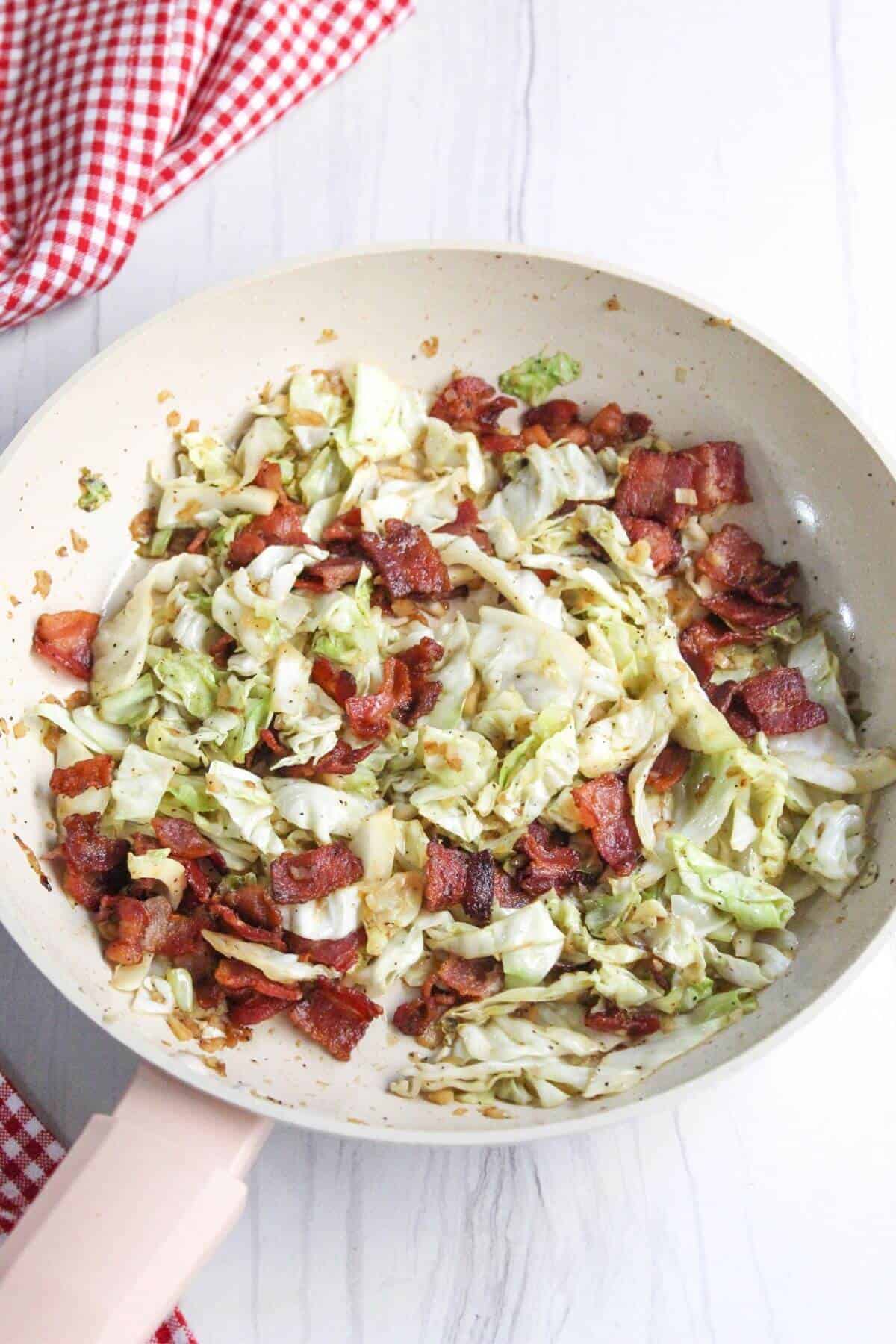 Finished Southern fried cabbage with bacon in skillet.