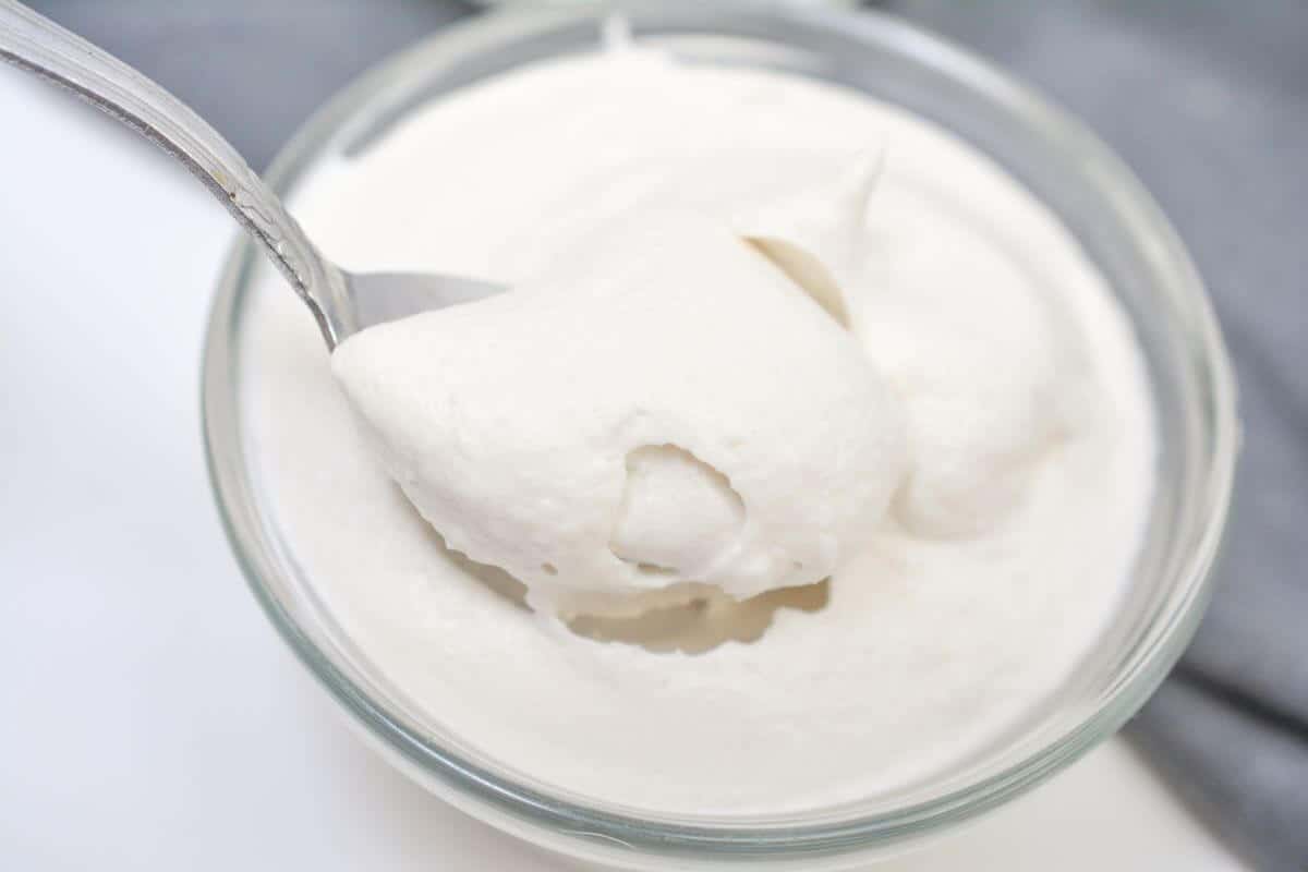Whipped coconut cream with spoon in it.
