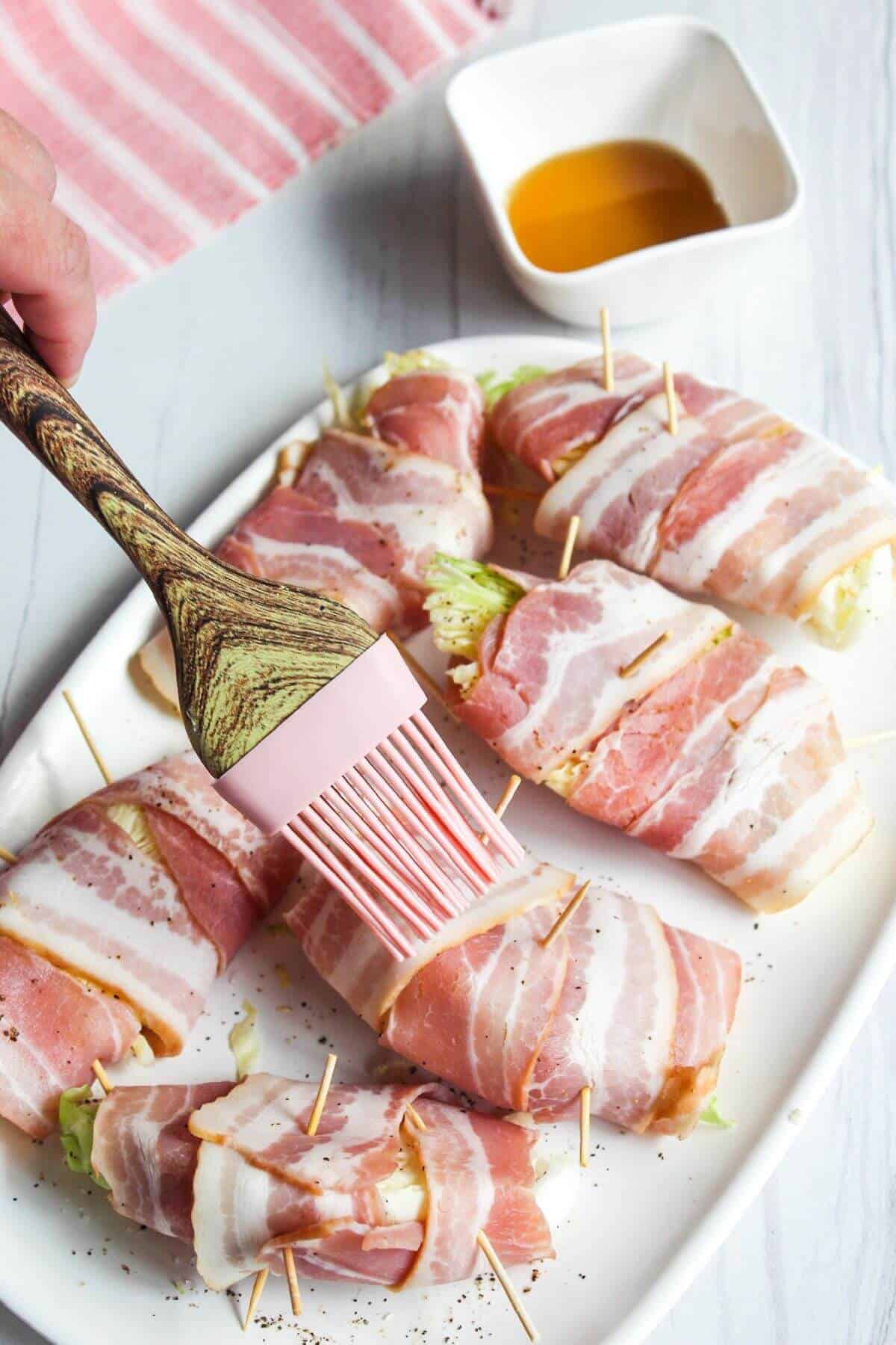 Brushing maple syrup on bacon wrapped cabbage.