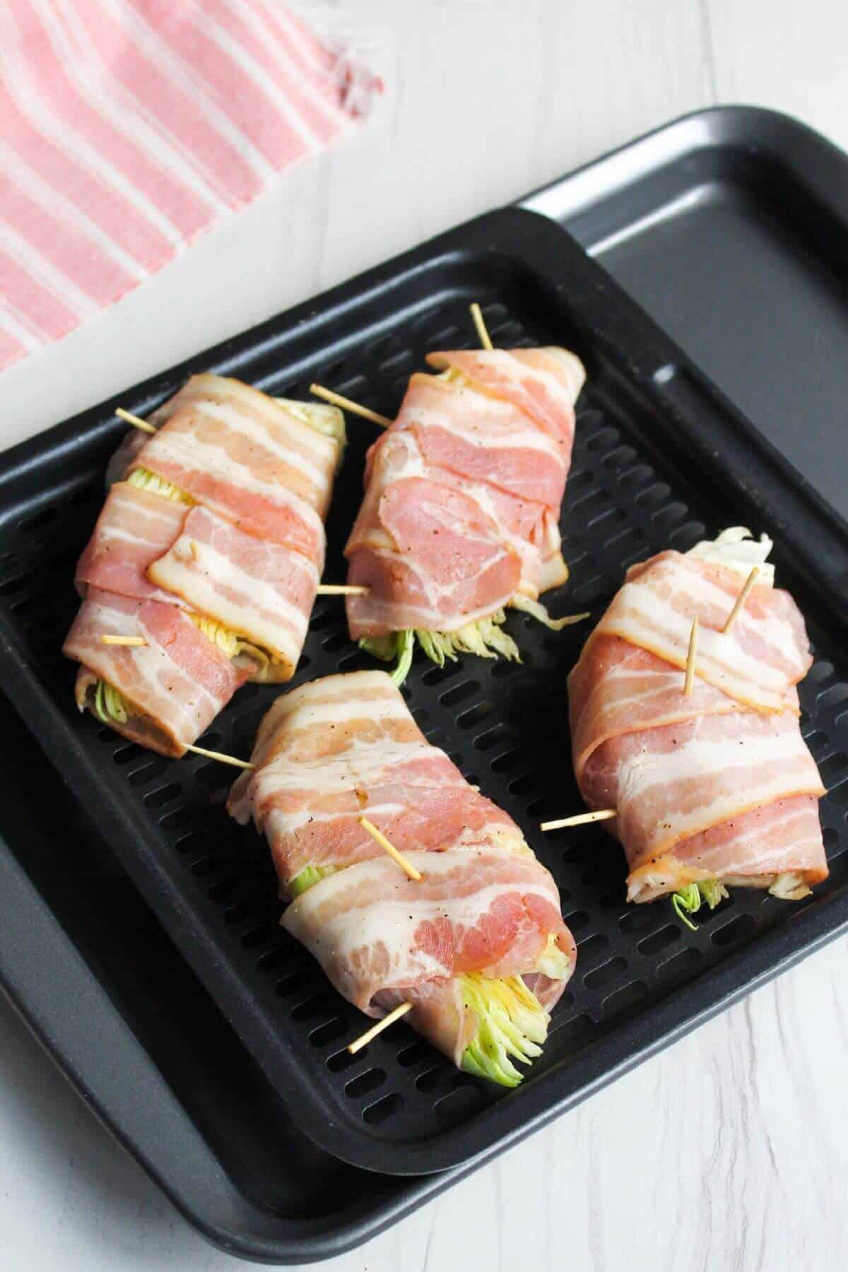 Bacon wrapped cabbage wedges on air fryer tray.
