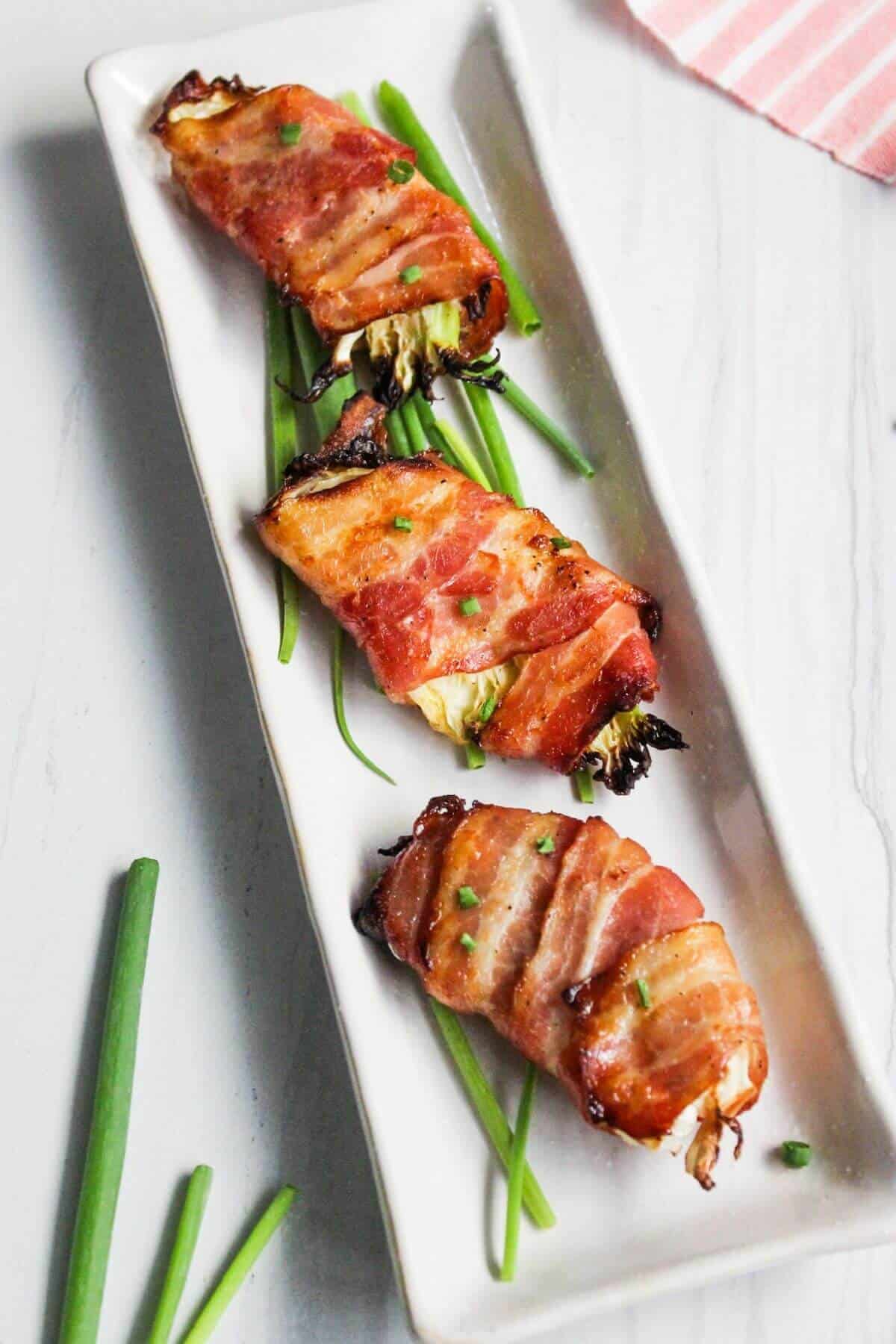 Bacon wrapped air fryer cabbage wedges on rectangular platter.