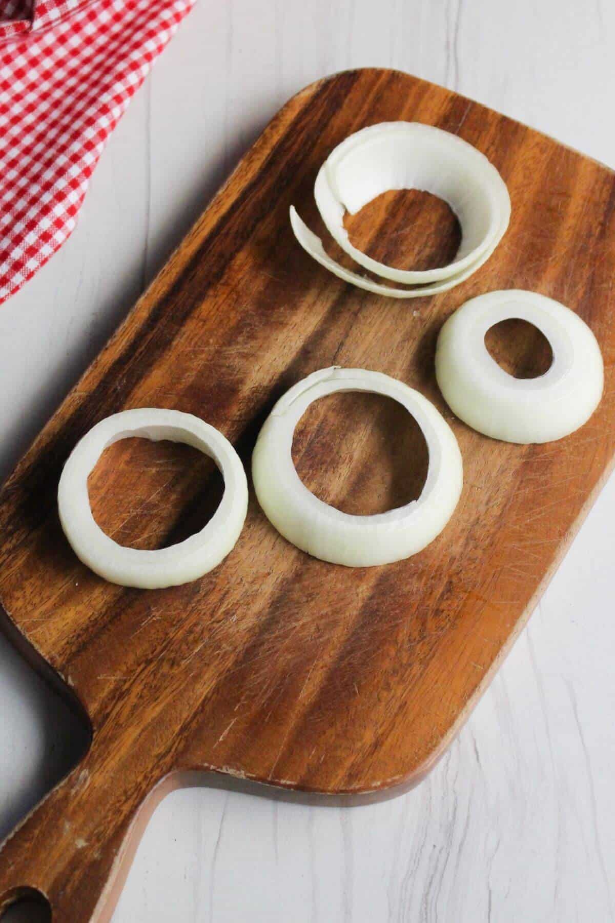 Onion sliced into rings on cutting board.