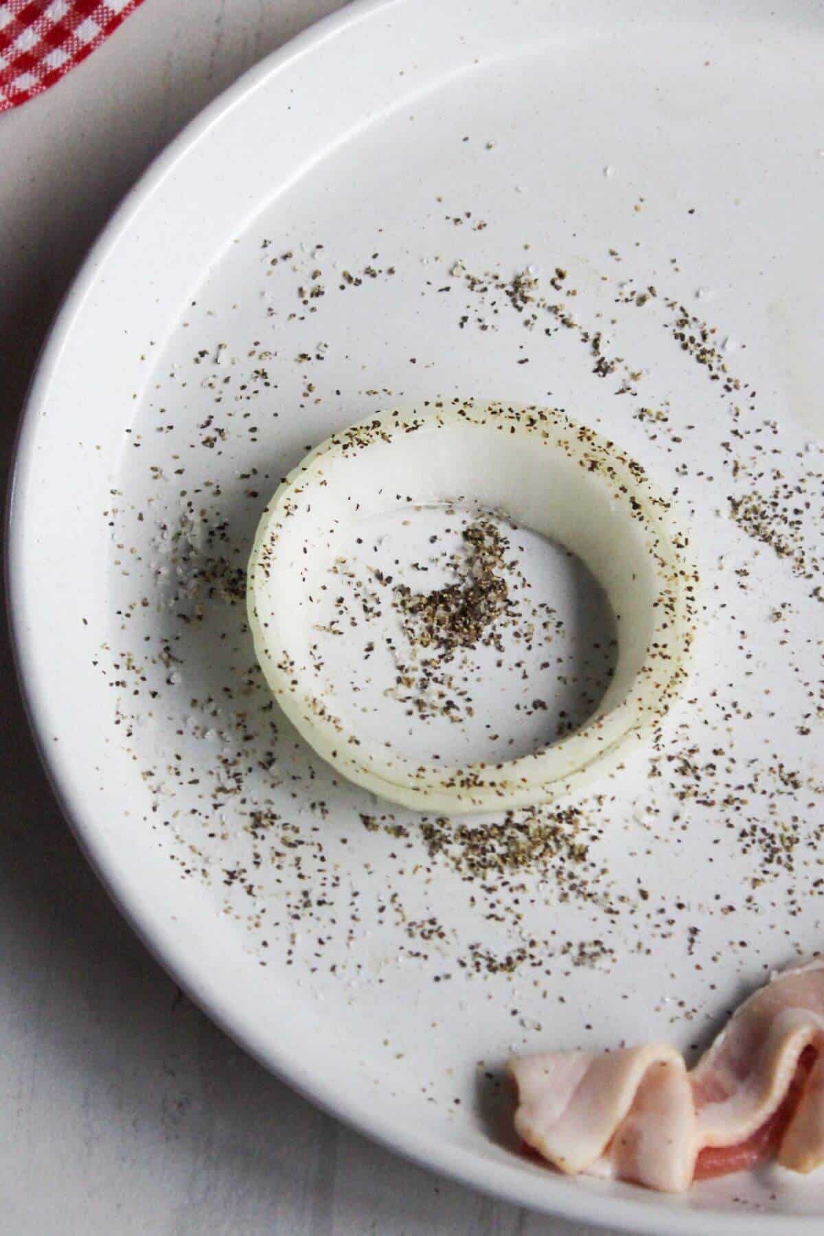 Salt and pepper sprinkled onto ring of onion.