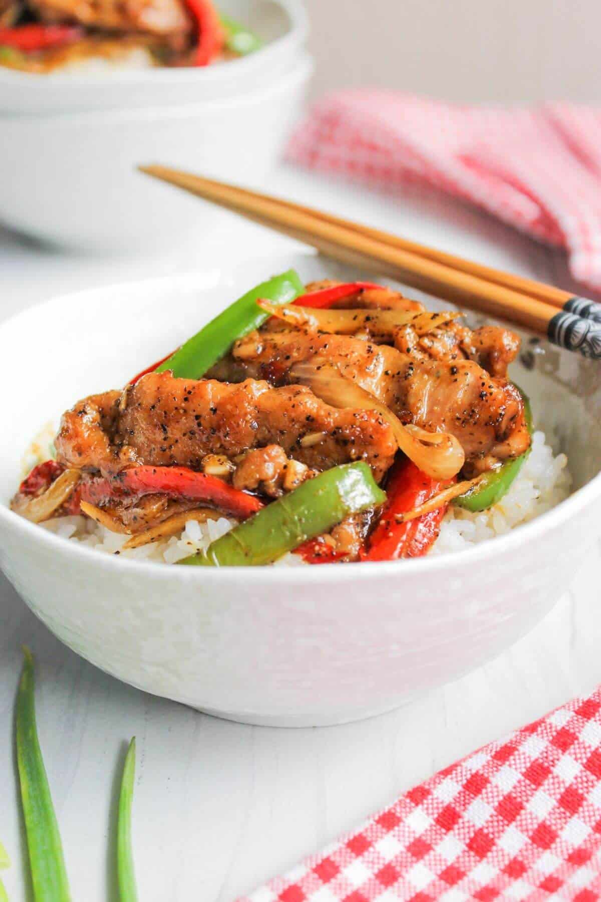 Black pepper chicken served with rice in bowl.