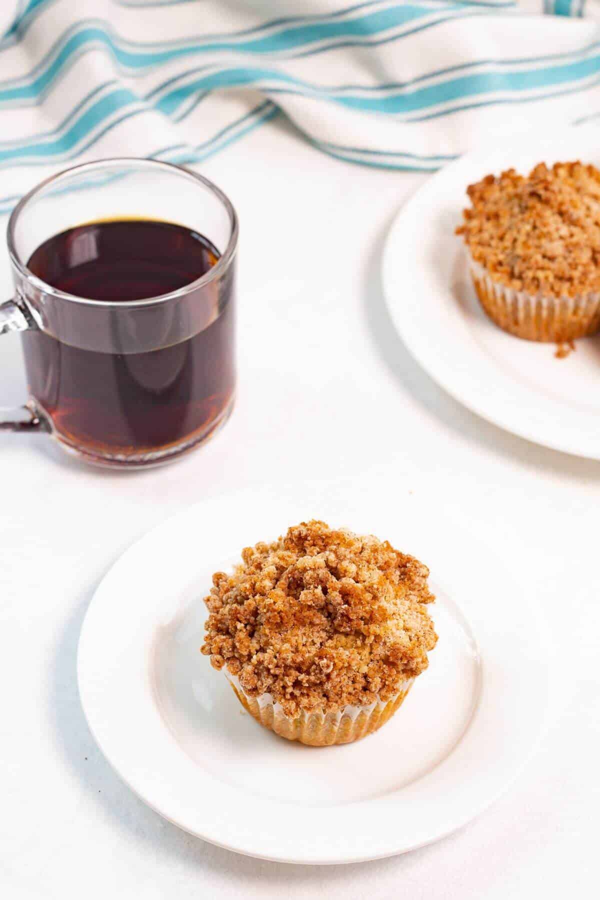Cinnamon coffee cake muffins on white plates with coffee.