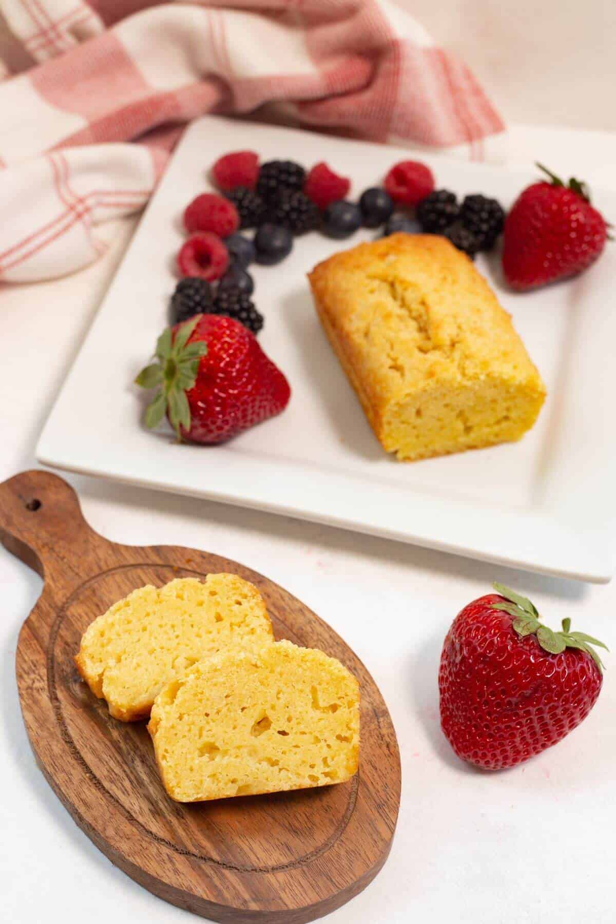 Pound cake on square plate with slices on cutting board.