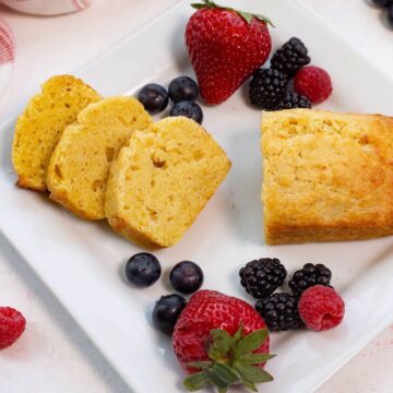 Mini pound cake sliced o square plate with berries.