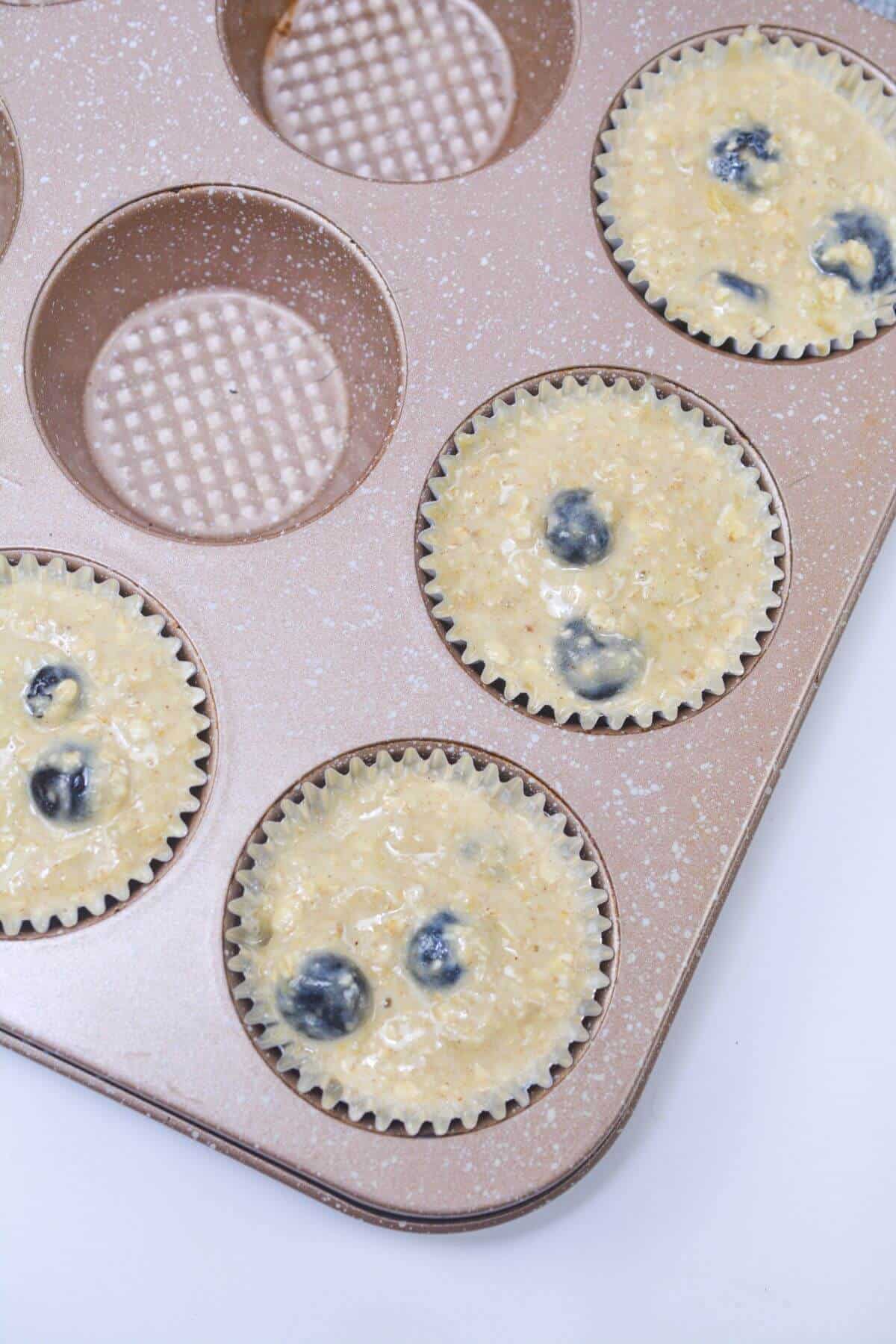 Muffin batter in paper lined muffin tins.