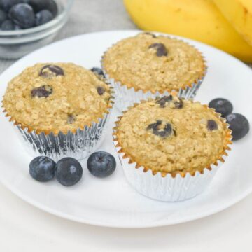 Three oat blueberry muffins on a plate.