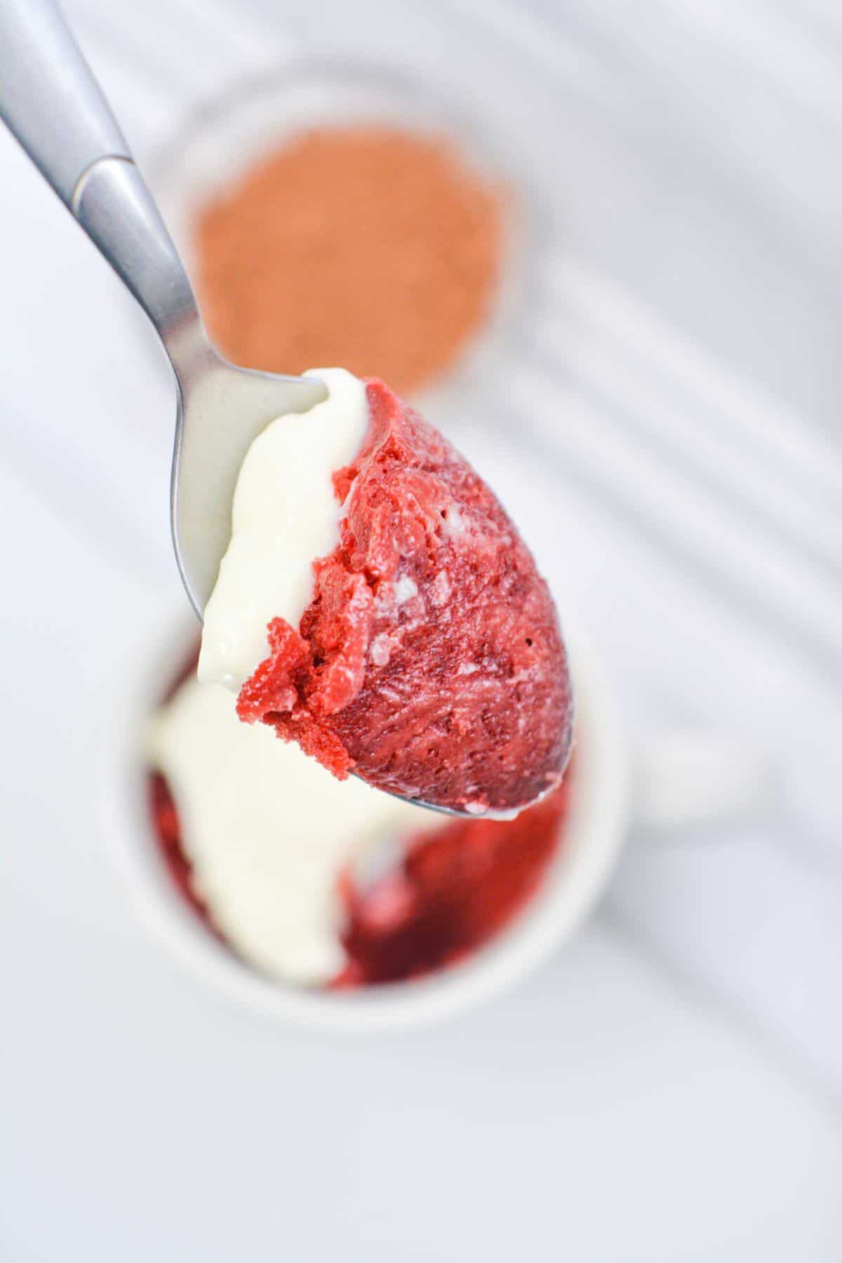 Frosted red velvet cake on spoon.
