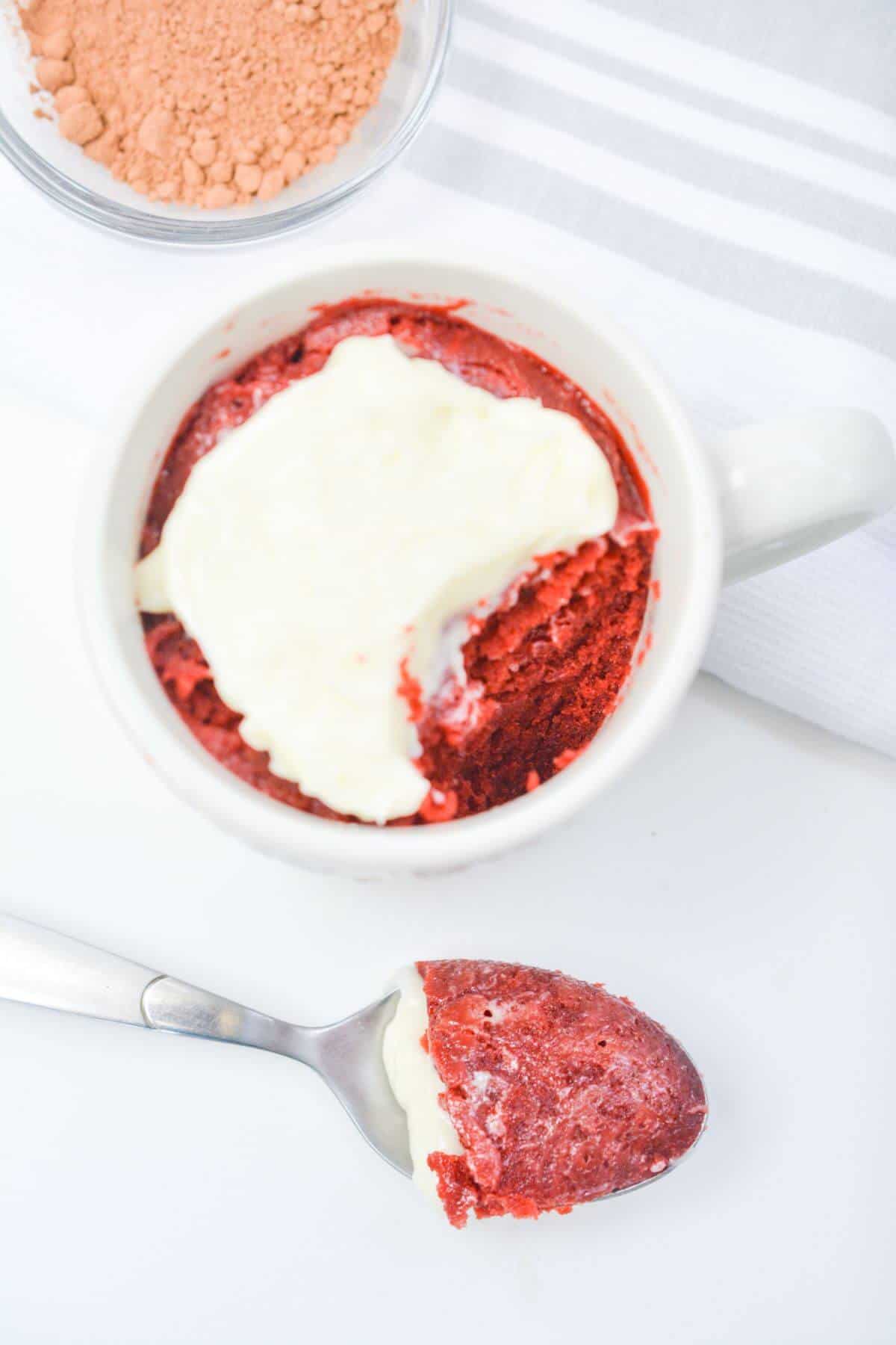 Red velvet mug cake with spoonful taken out.