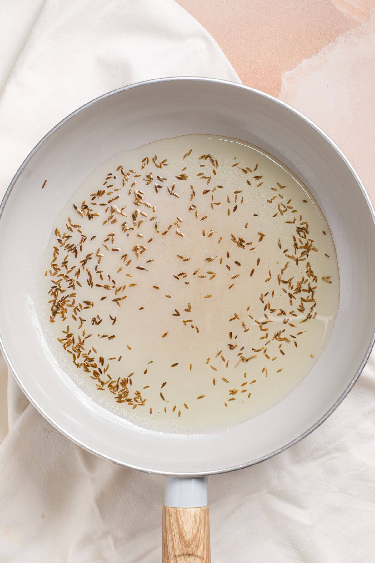 Cumin seeds in hot oil skillet.