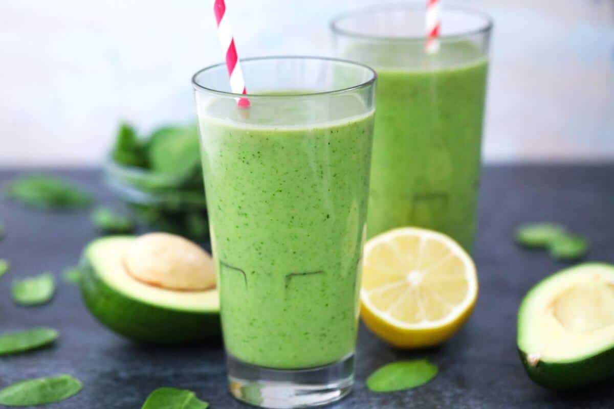 Two tall glasses with green beverages and striped straws.