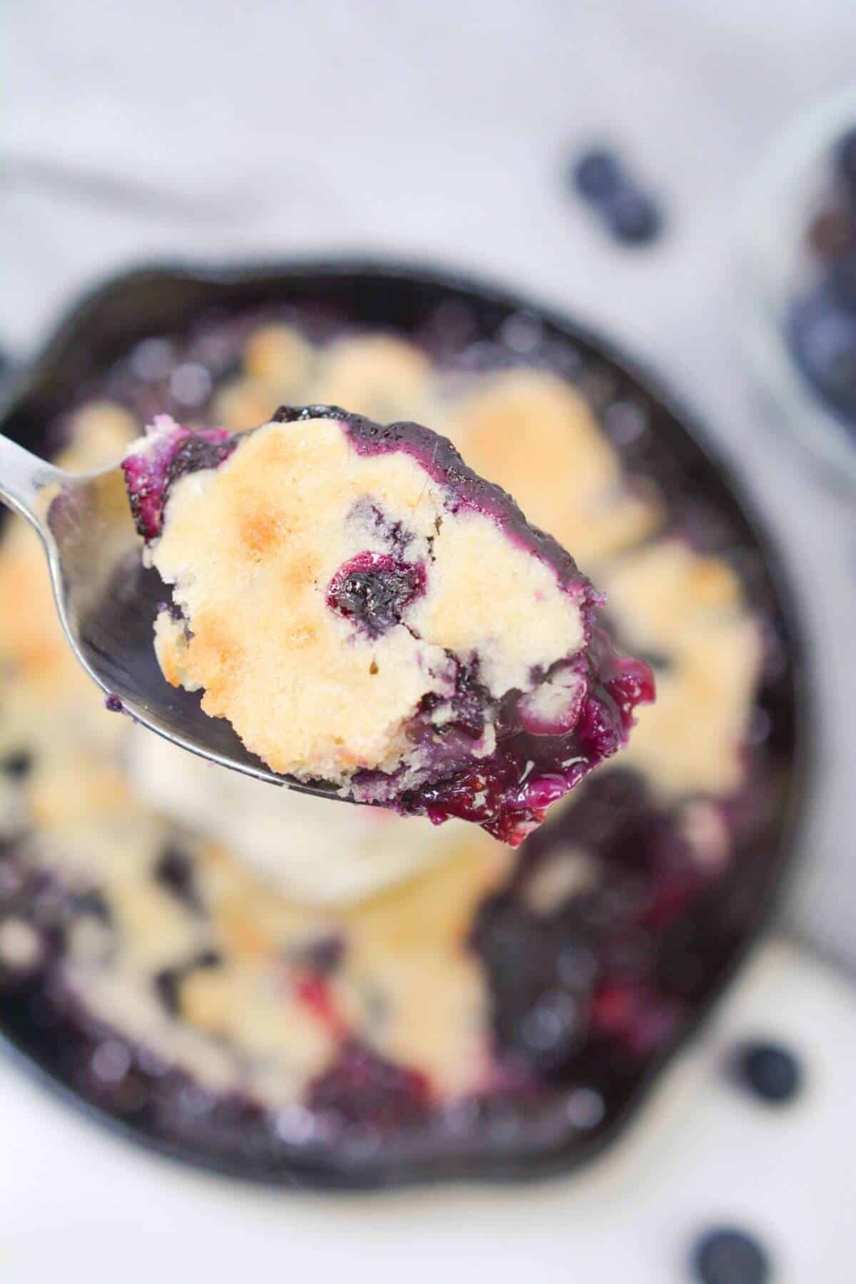 Spoon of cobbler over cobbler with ice cream.