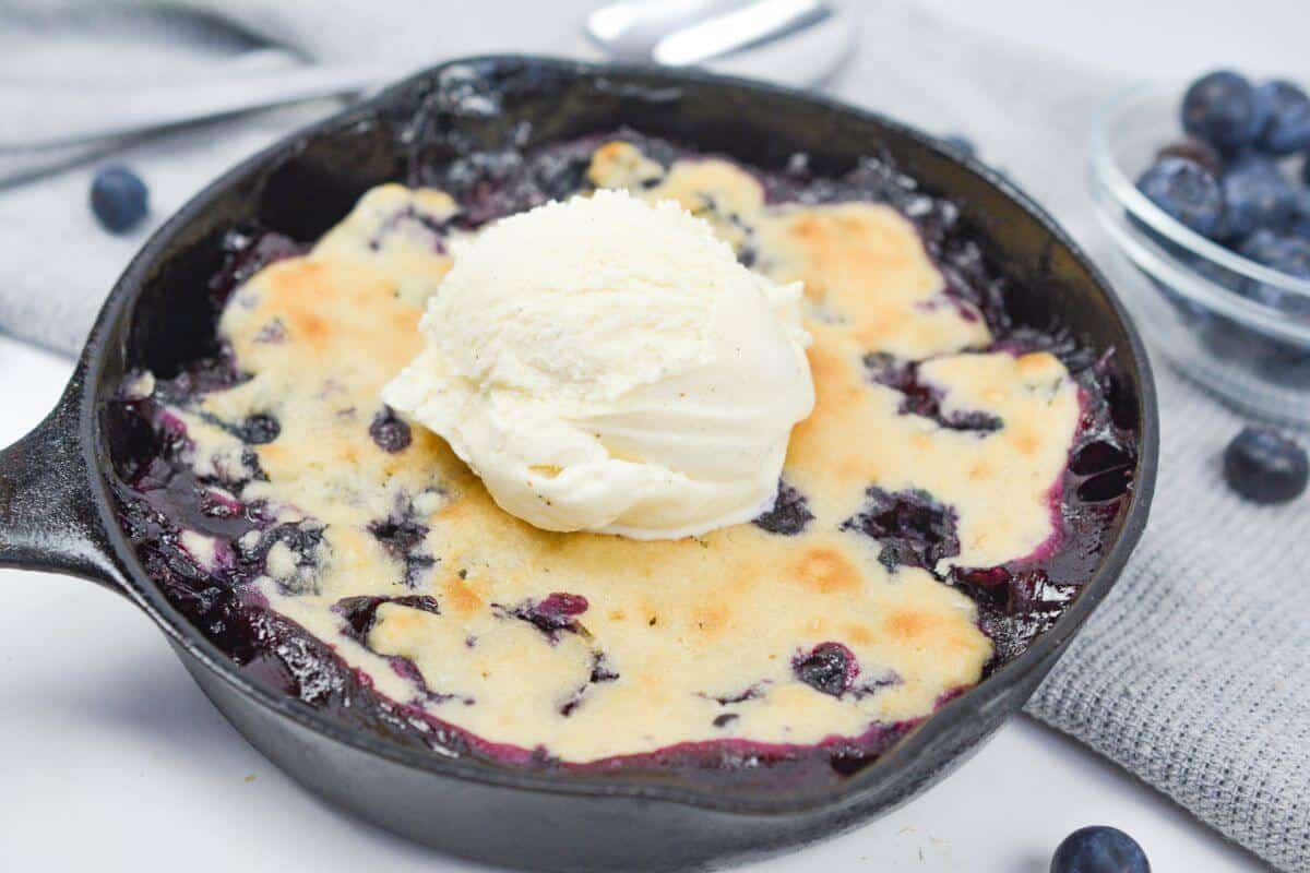 Scoop of vanilla ice cream over blueberry cobbler.