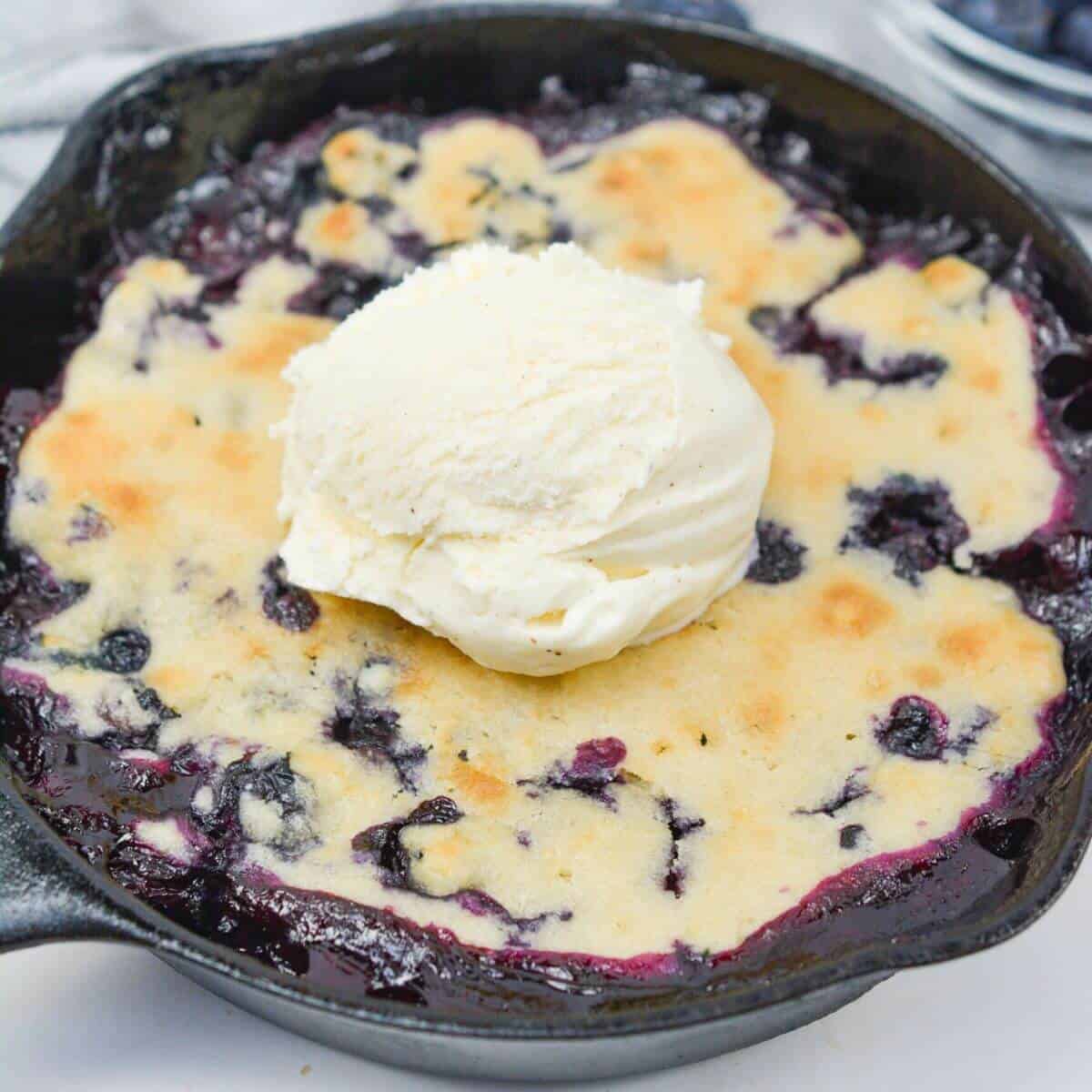 Cobbler in cast iron skillet with vanilla ice cream on top.