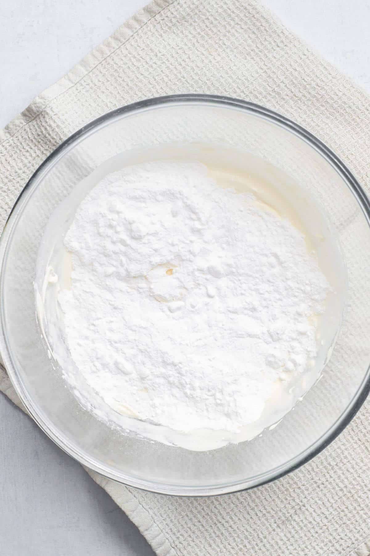 Sugar added to whipped cream in mixing bowl.