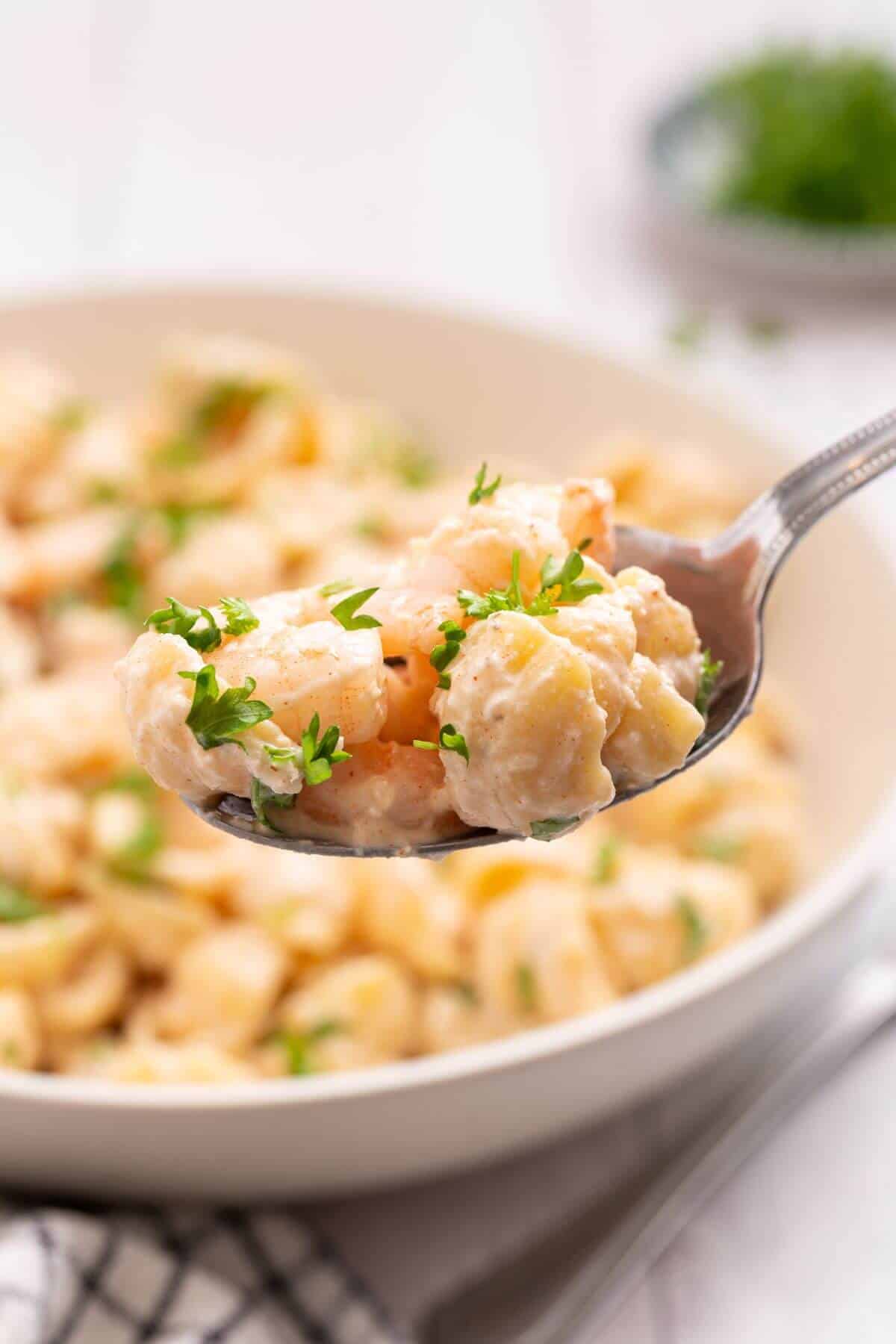 Seafood pasta salad on spoon over bowl.