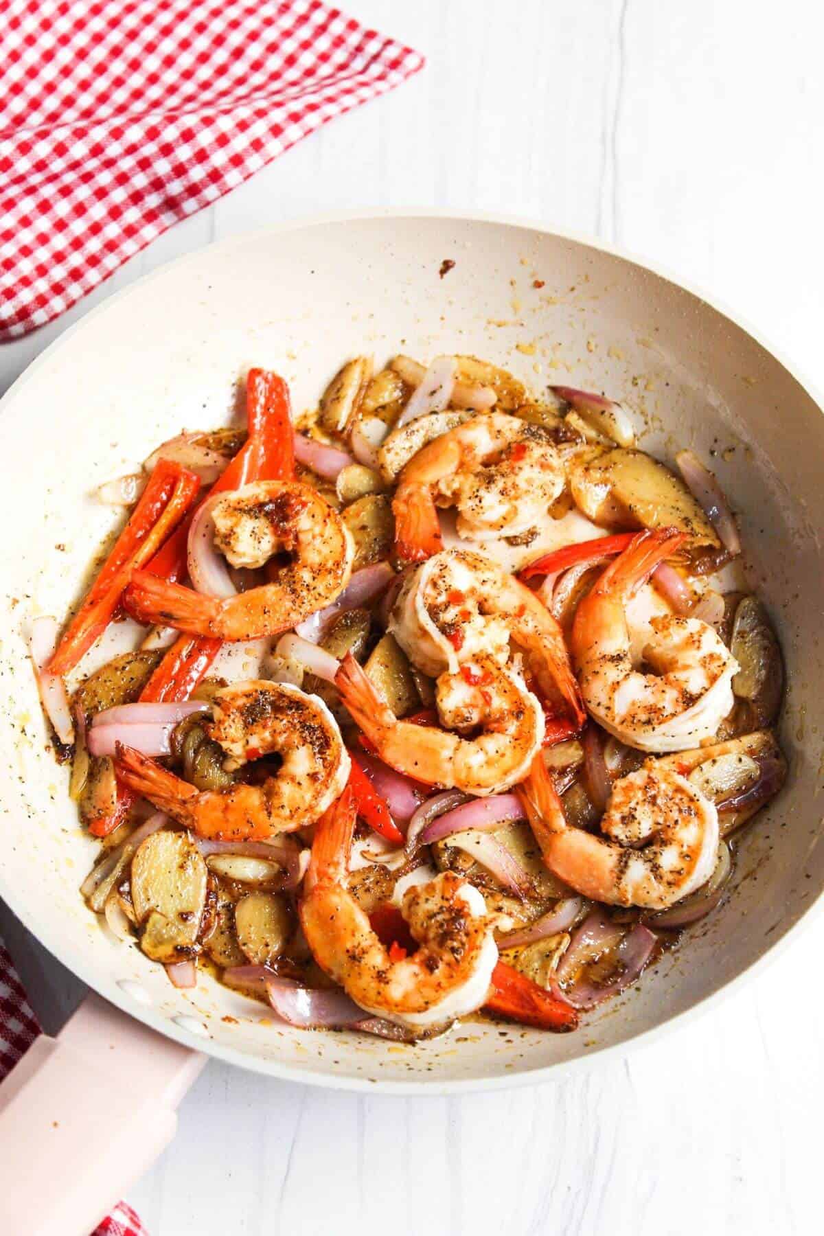 Cooked shrimp added to onion and peppers in skillet.