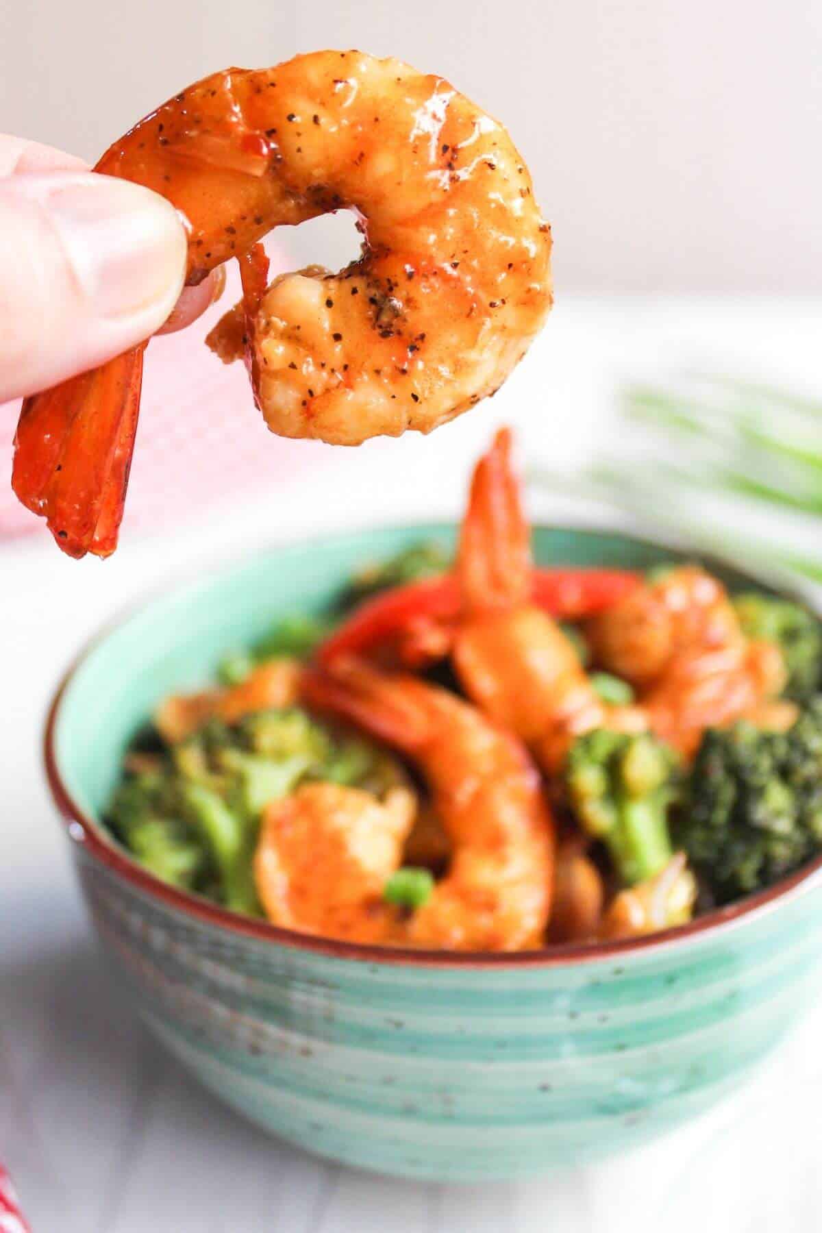Holding shrimp over bowl of food.