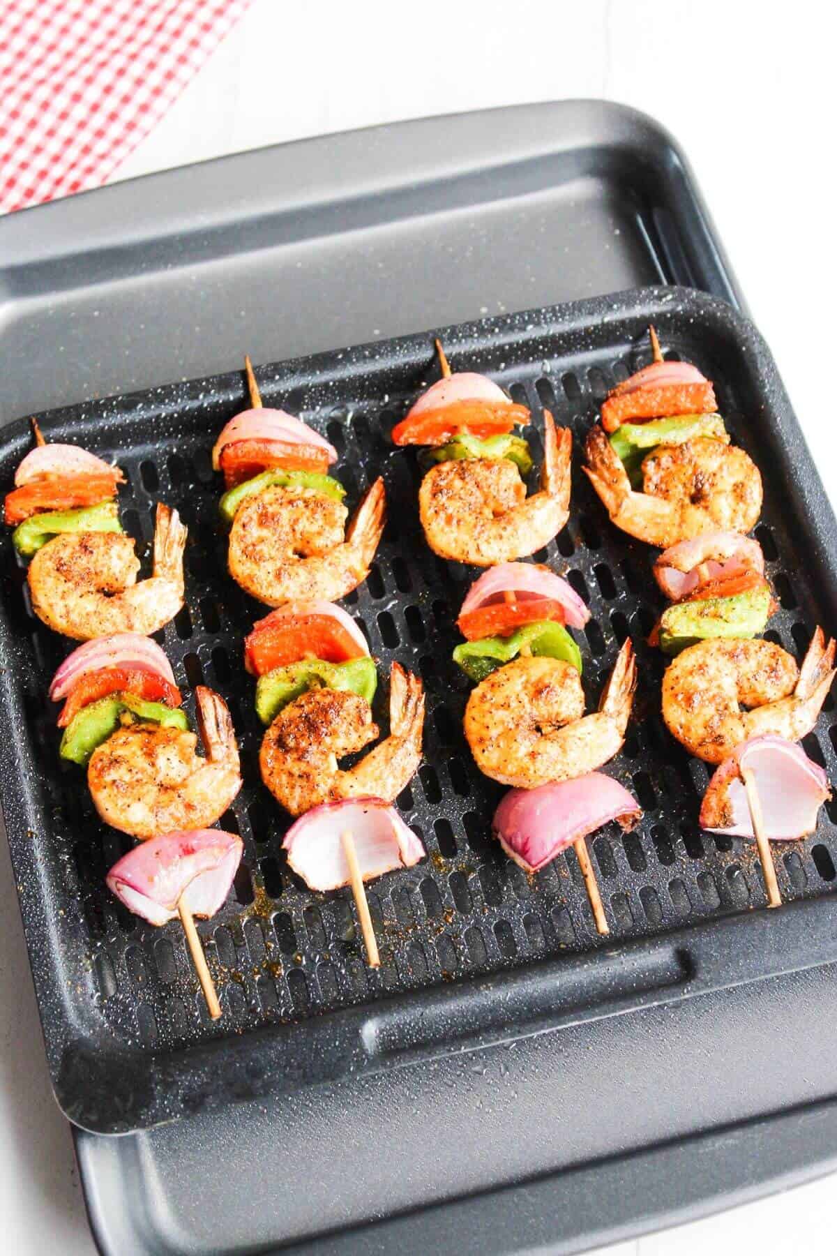 Cooked shrimp skewers on air fryer tray.