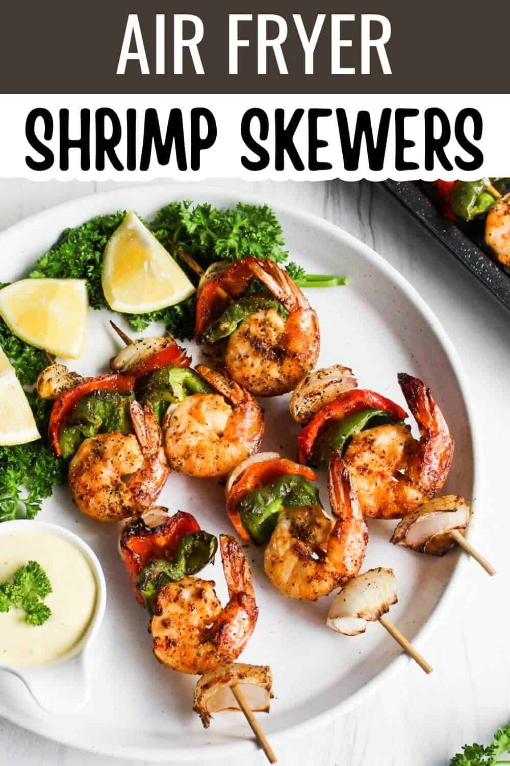 Grilled shrimp skewers on plate with lemons and dip.