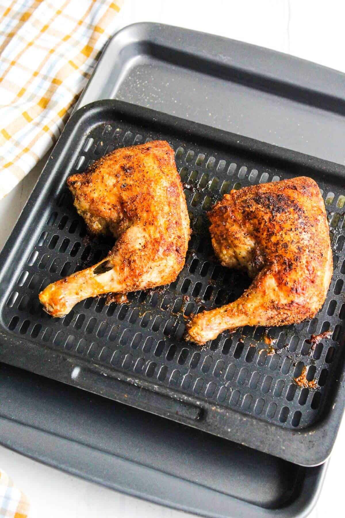 Cooked chicken legs on air fryer tray.