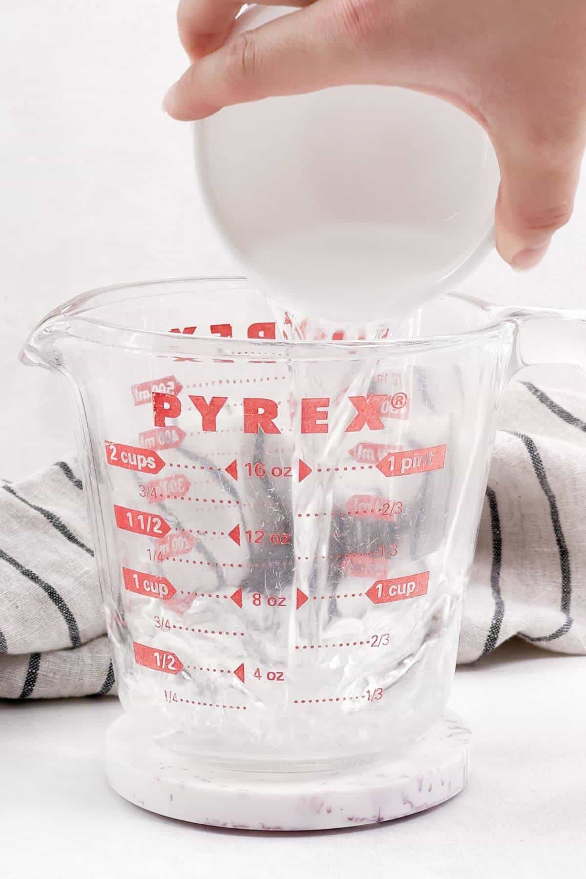 Pouring water into Pyrex measuring cup.