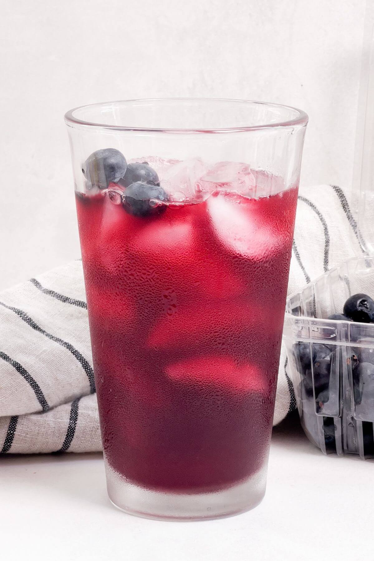 Garnishing blueberry lemonade cocktail with fresh blueberries.