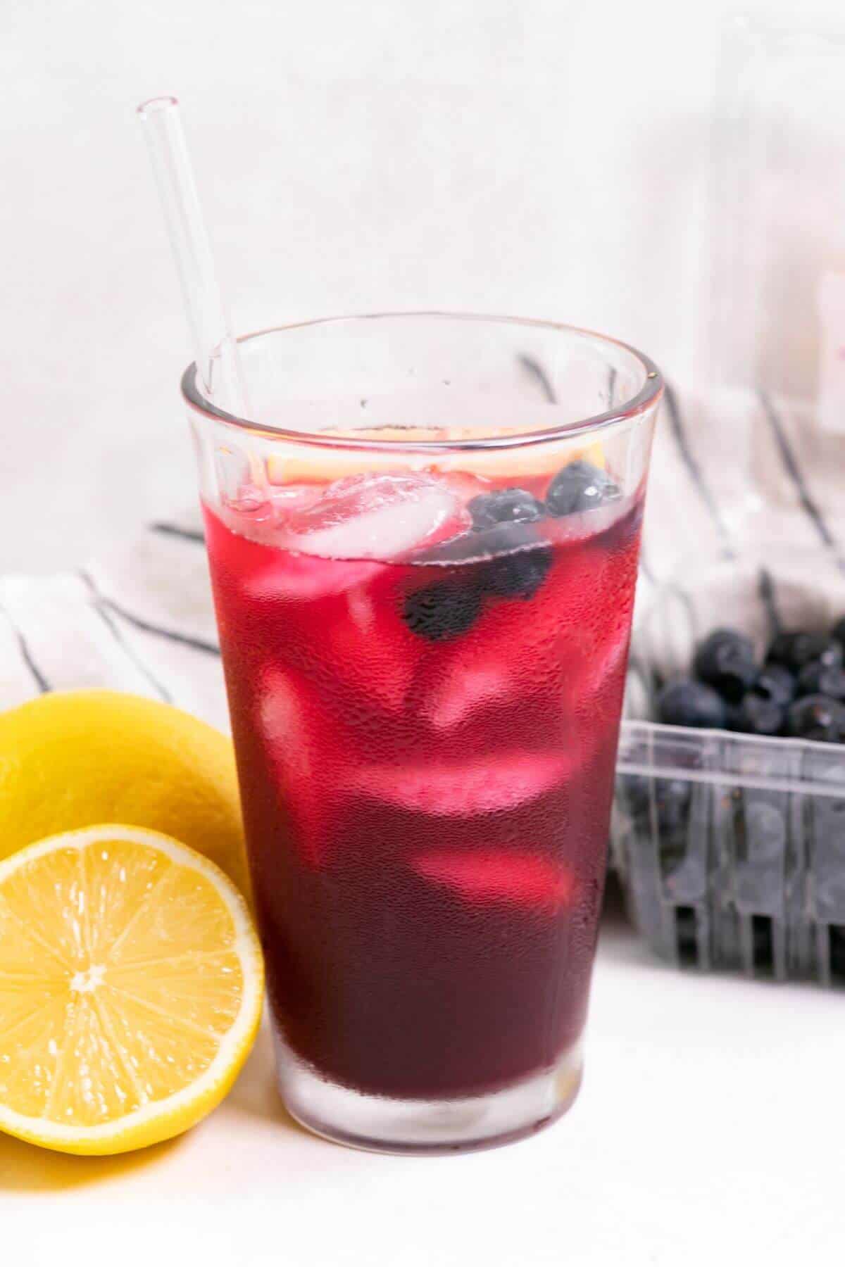 Blueberry vodka lemonade with sliced lemon and a pint of blueberries.