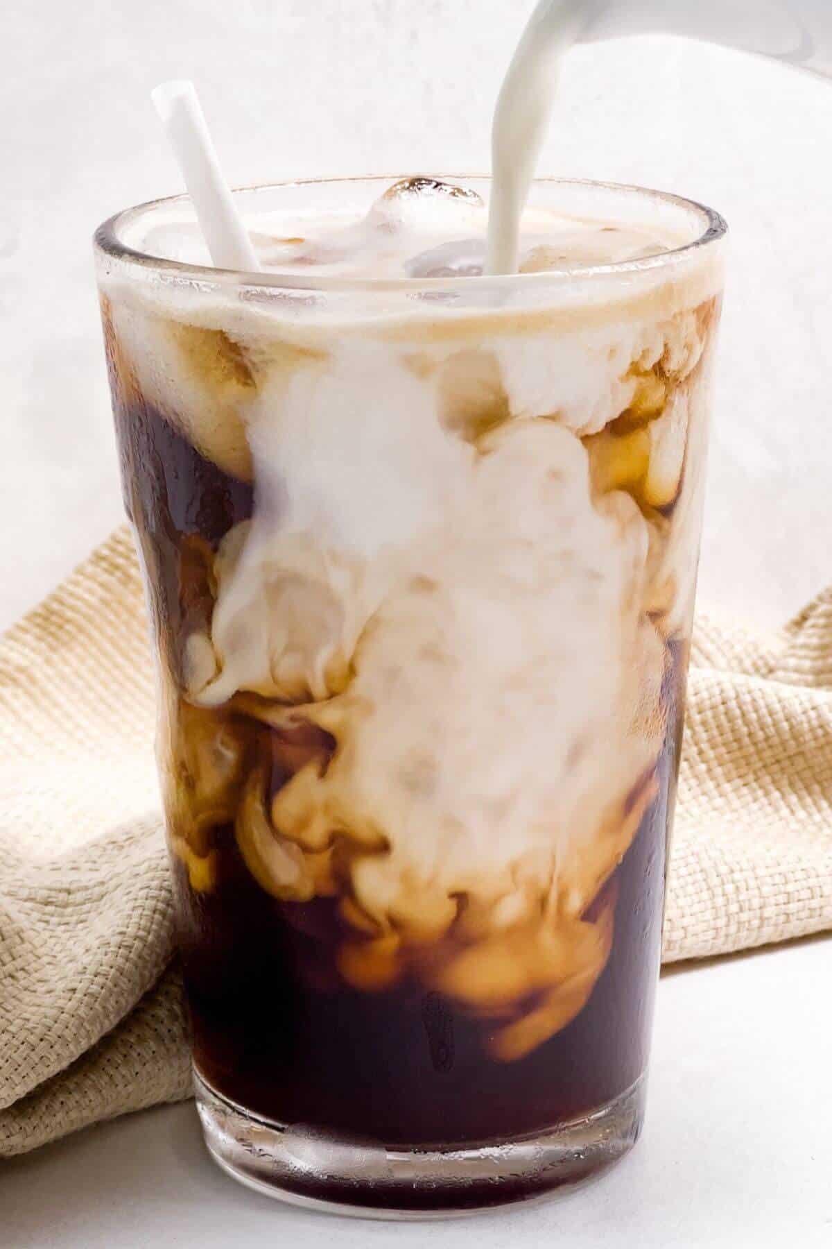 Adding cream to the iced Americano.