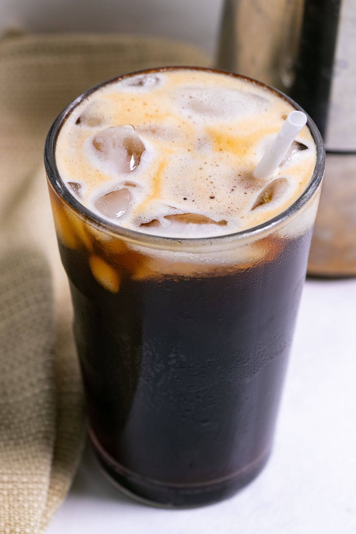 Black iced Americano in tall glass with straw.