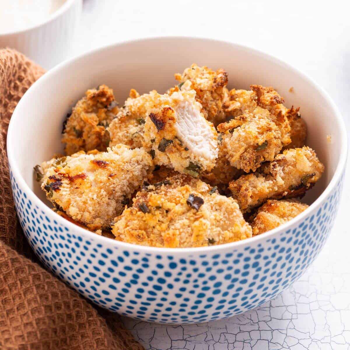 Popcorn chicken in bowl with one piece bitten.