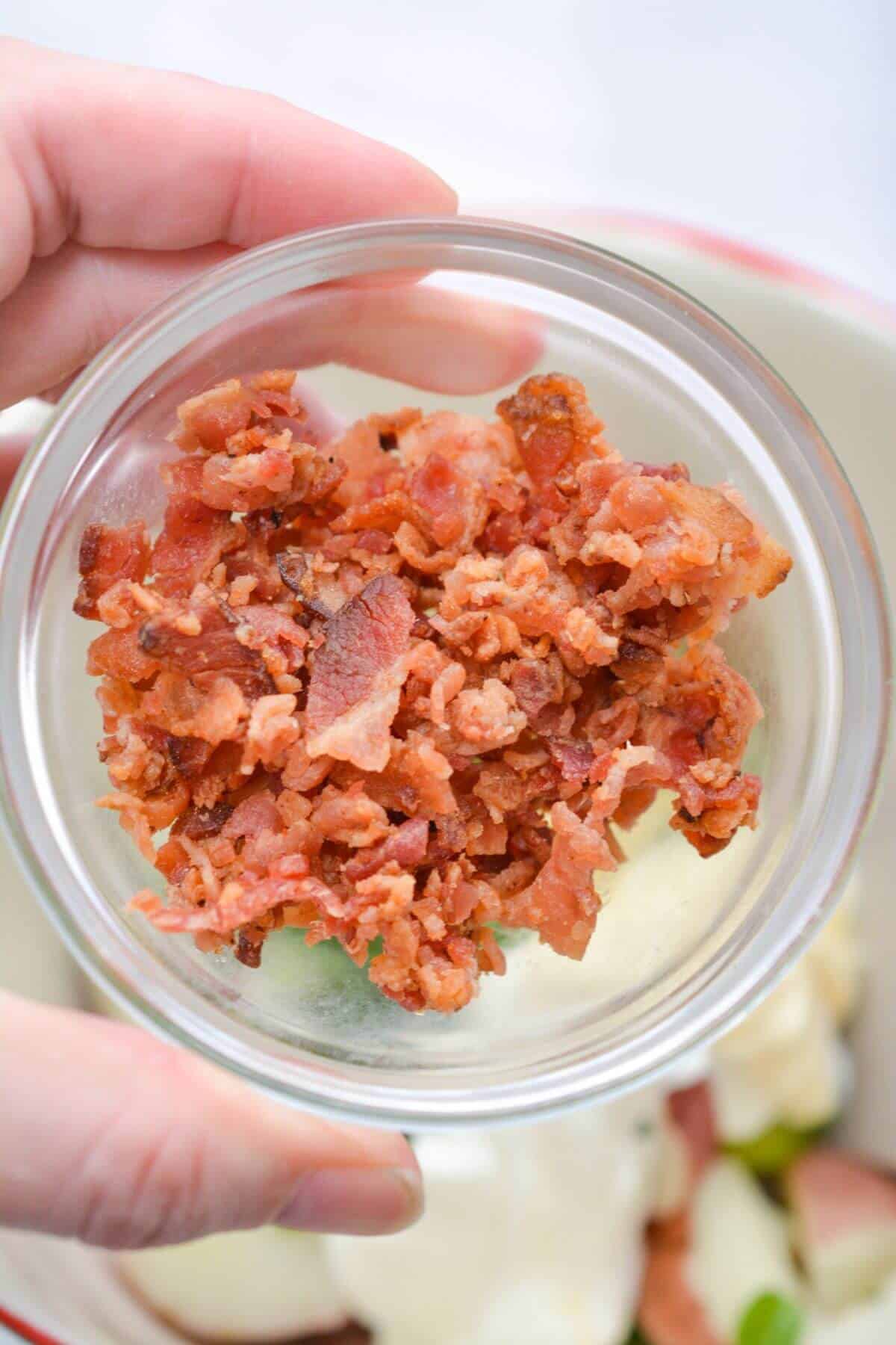 Adding chopped bacon to the red skin potato salad.