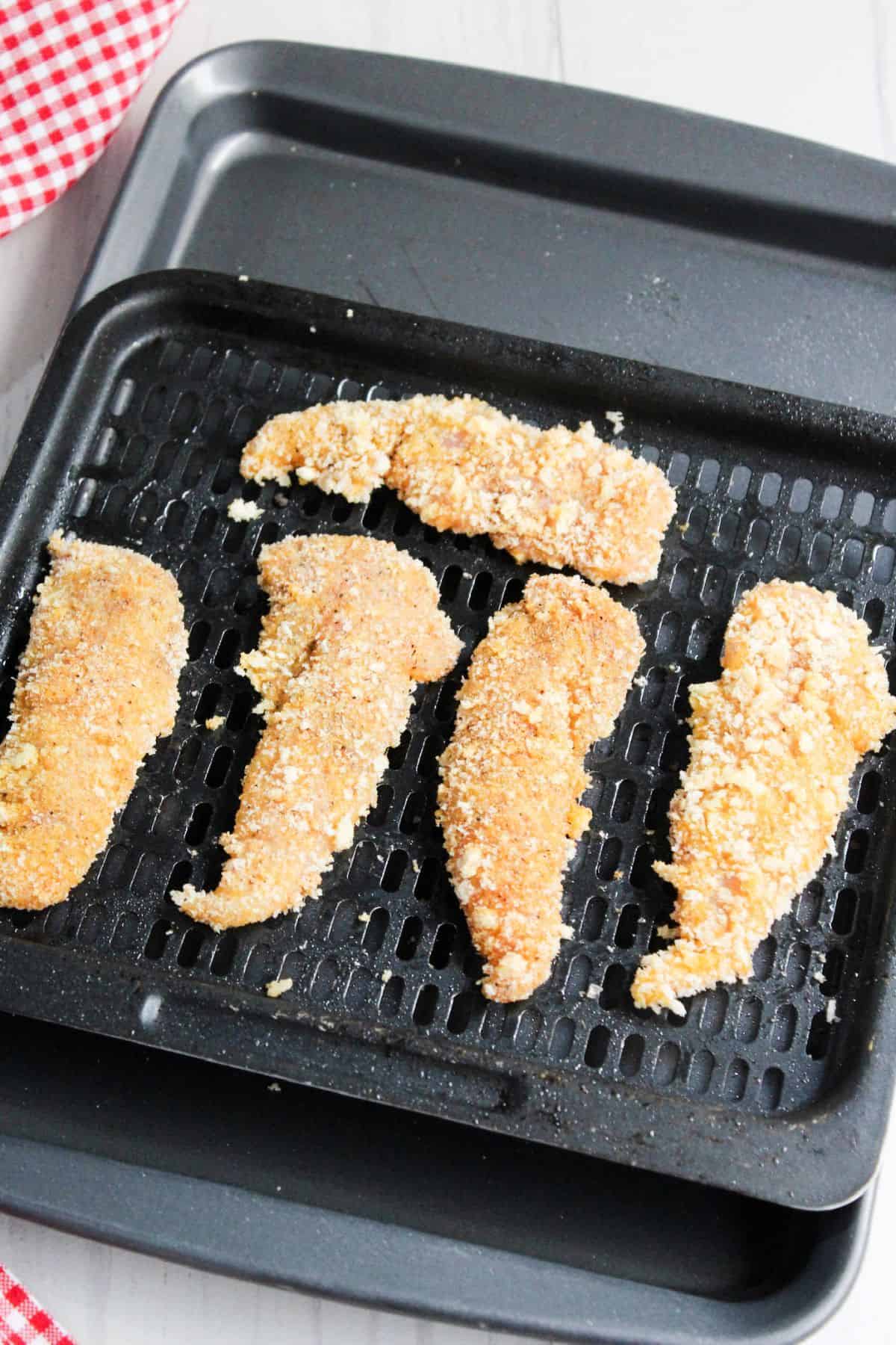 Prepared chicken tenders on air fryer tray.