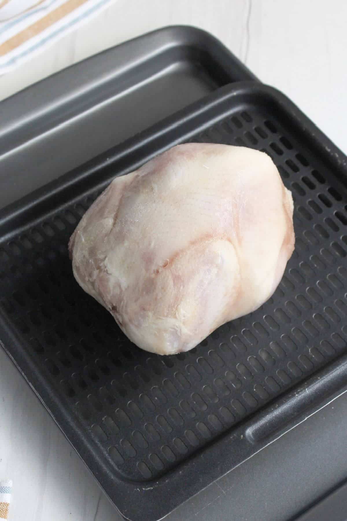 Frozen cornish hen on air fryer tray.