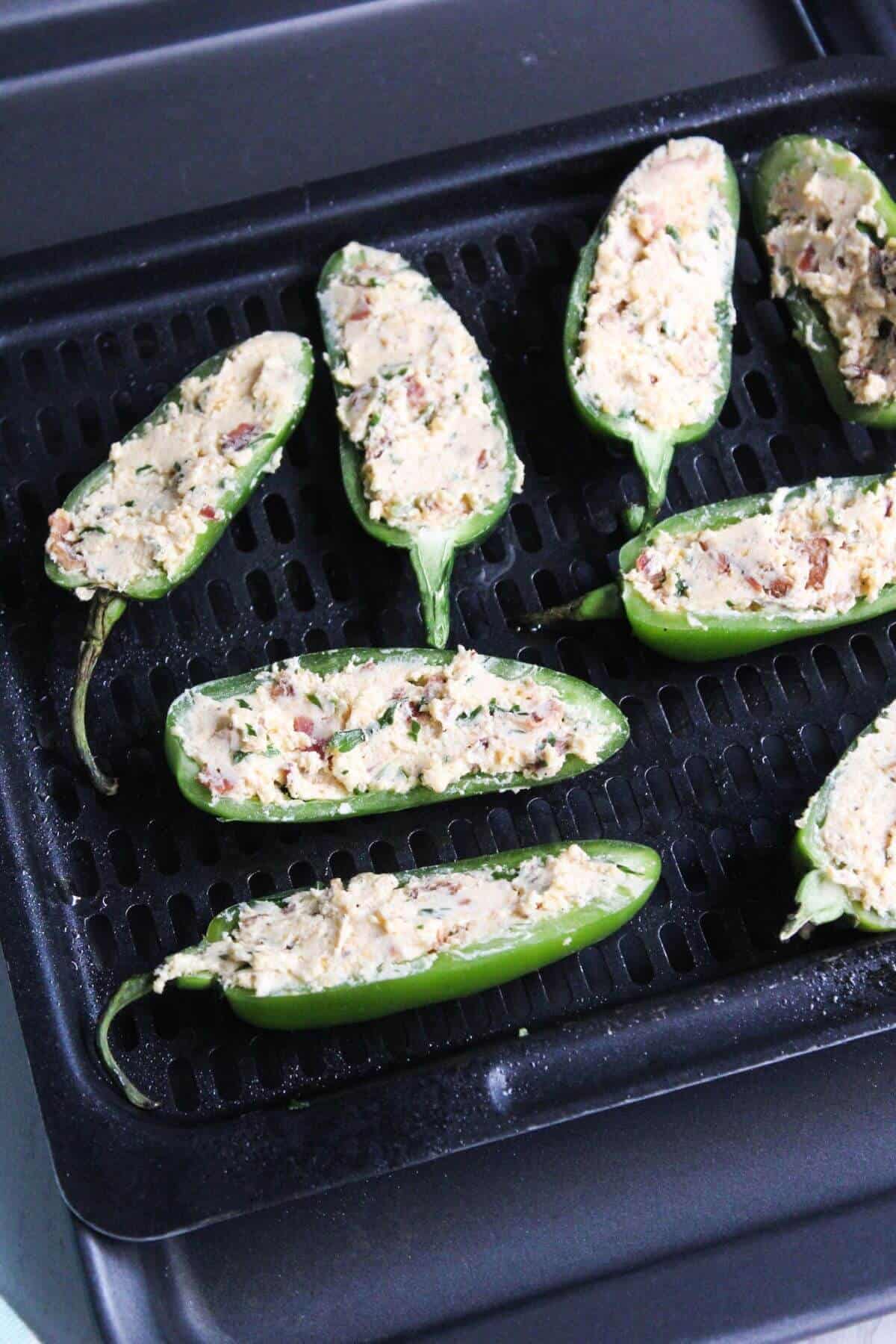 Peppers stuffed with filling on air fryer tray.