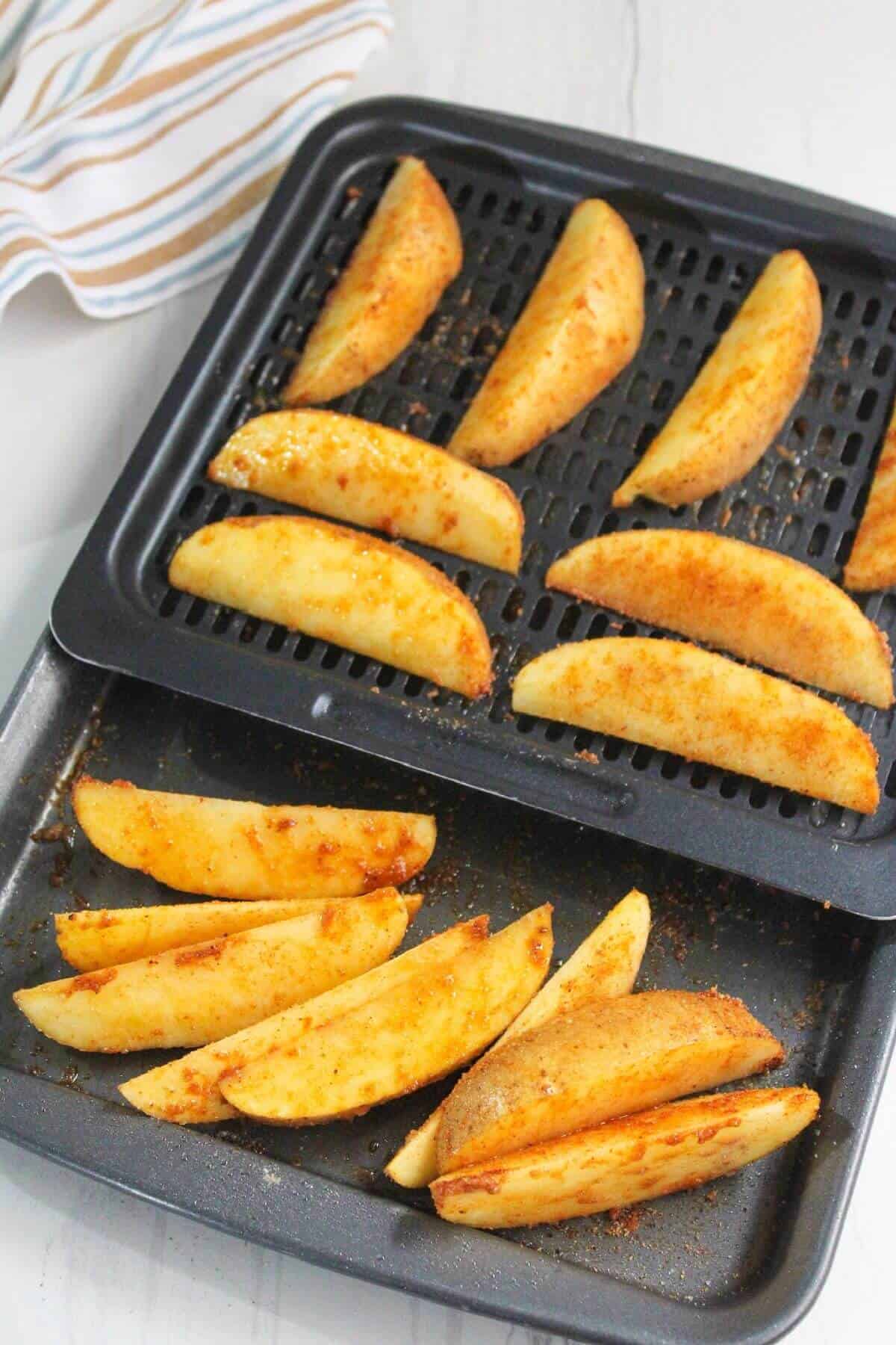 Potato wedges on air fryer trays.